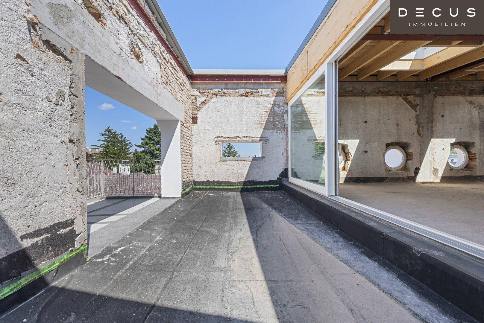 Dachterrasse im Rohbau mit Blick auf die Umgebung und den Innenraum.