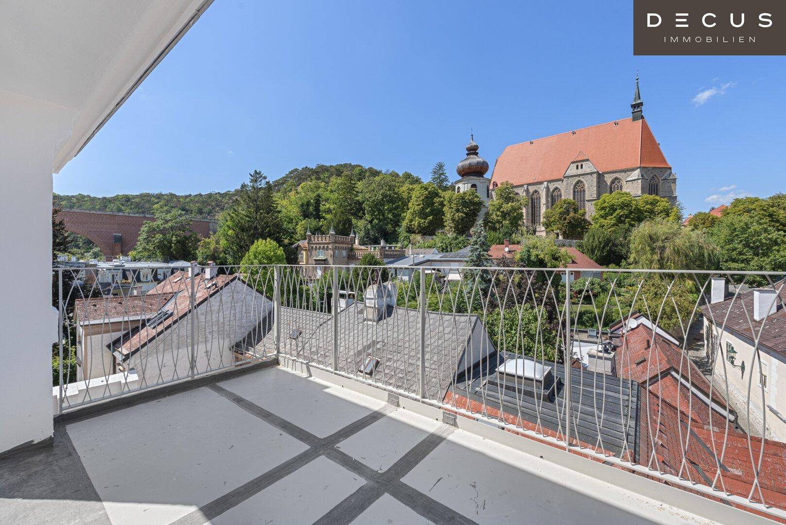 Weitläufige Dachterrasse mit Metallgeländer und Panoramablick über die Dächer der Stadt.