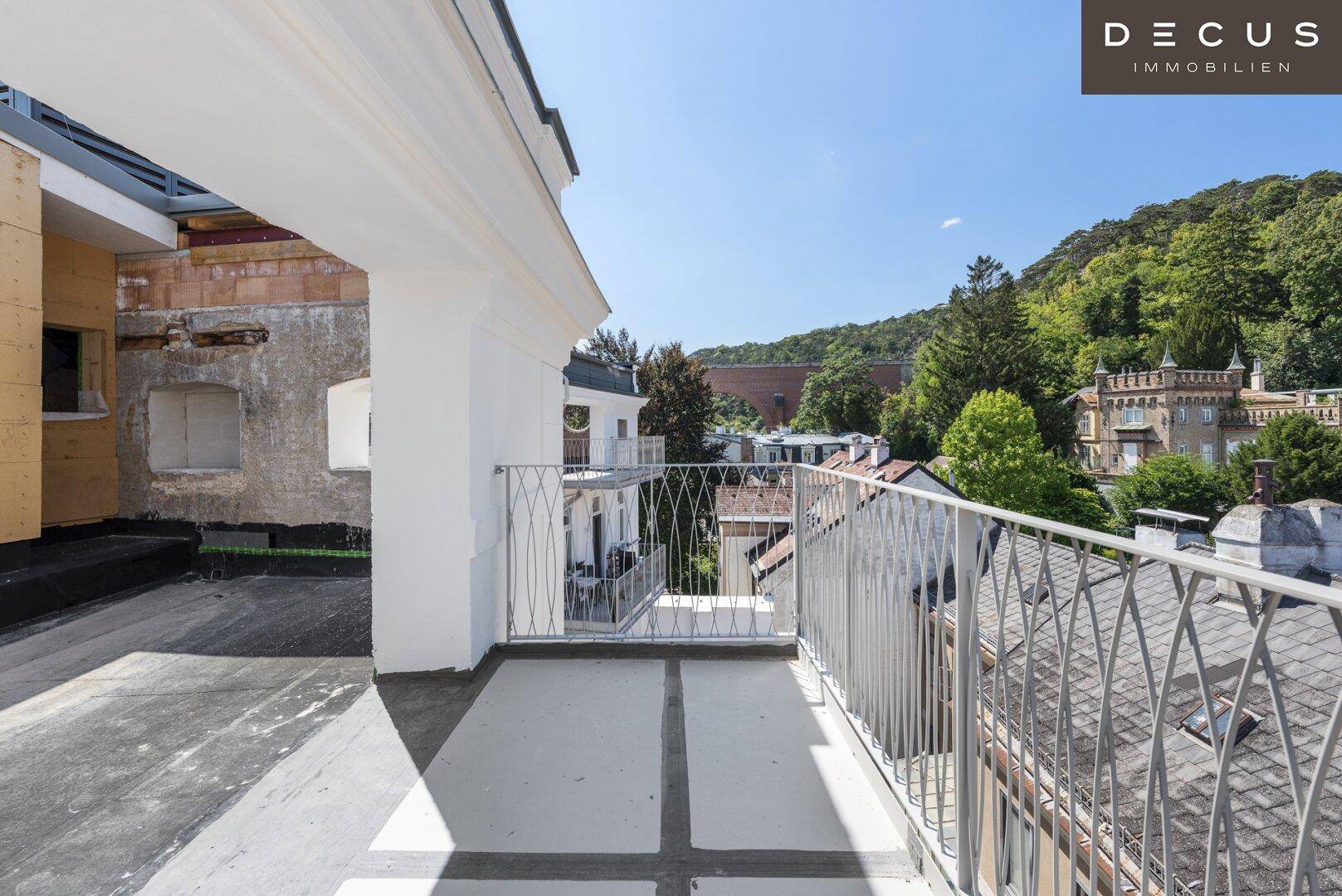 Langer Balkon mit Metallgeländer und Blick auf die umliegenden Gebäude und Hügel.