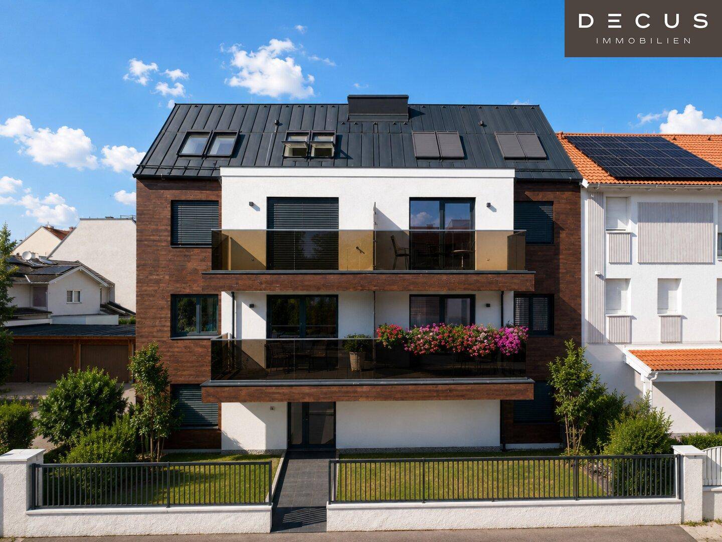 Moderne Wohnhausfassade mit Balkonen, großen Fenstern und Photovoltaikanlage auf dem Dach.