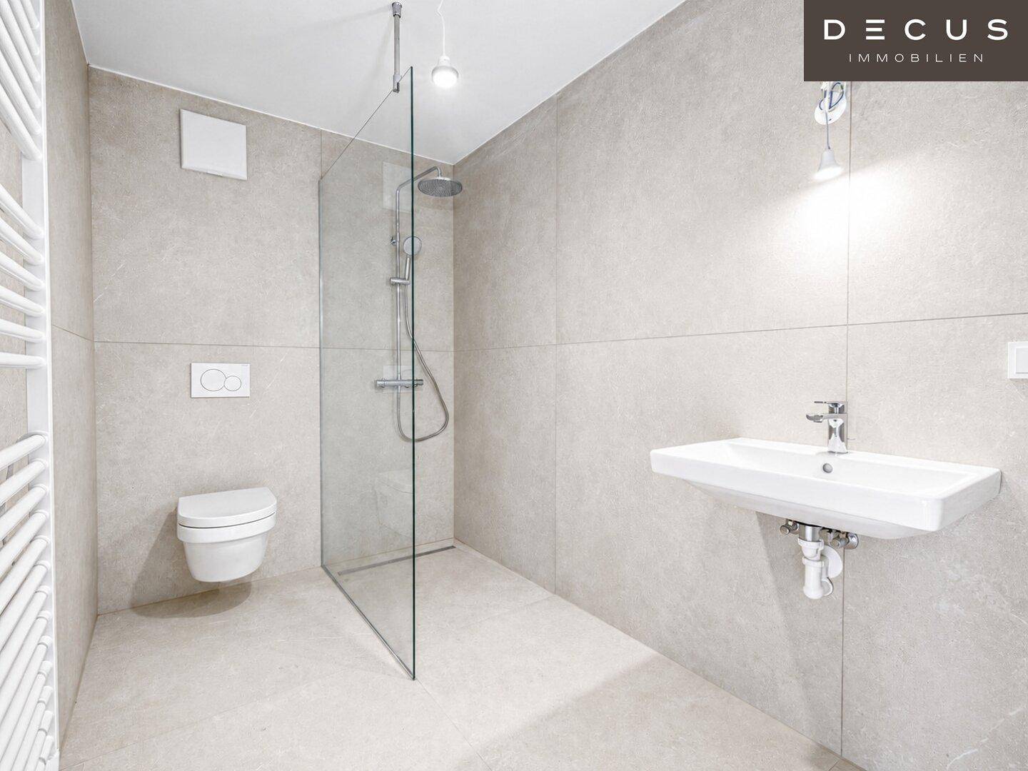 Modernes Badezimmer mit ebenerdiger Dusche, wandhängender Toilette und Waschbecken in hellen Fliesen.