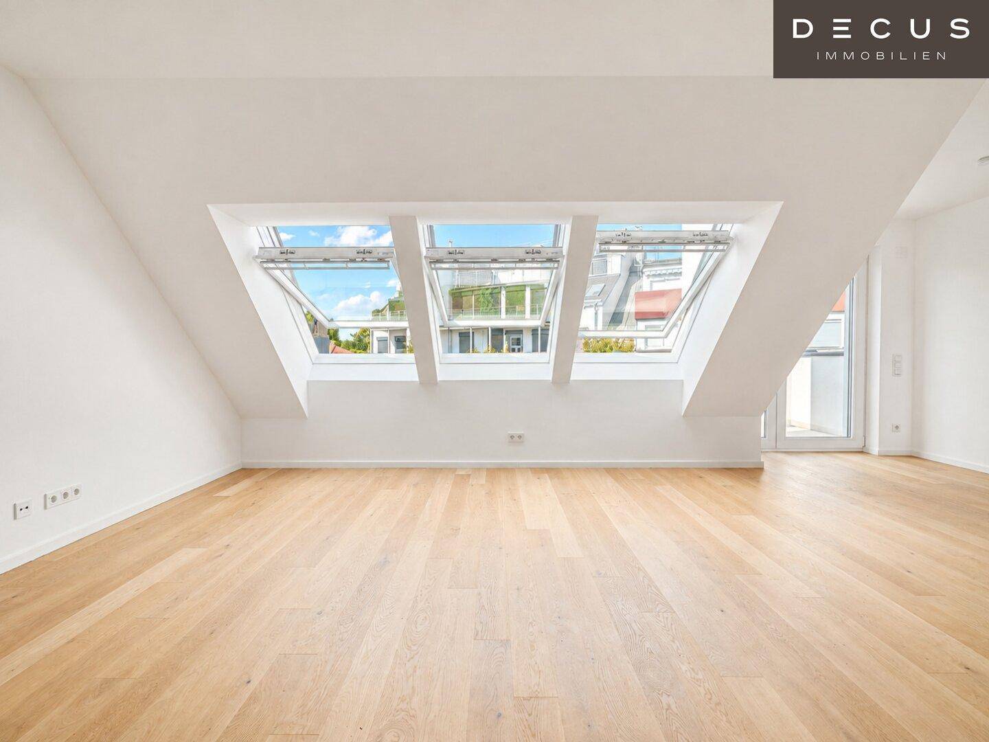 Lichtdurchfluteter Raum mit Holzboden und drei großen Dachfenstern, die viel Tageslicht hereinlassen.
