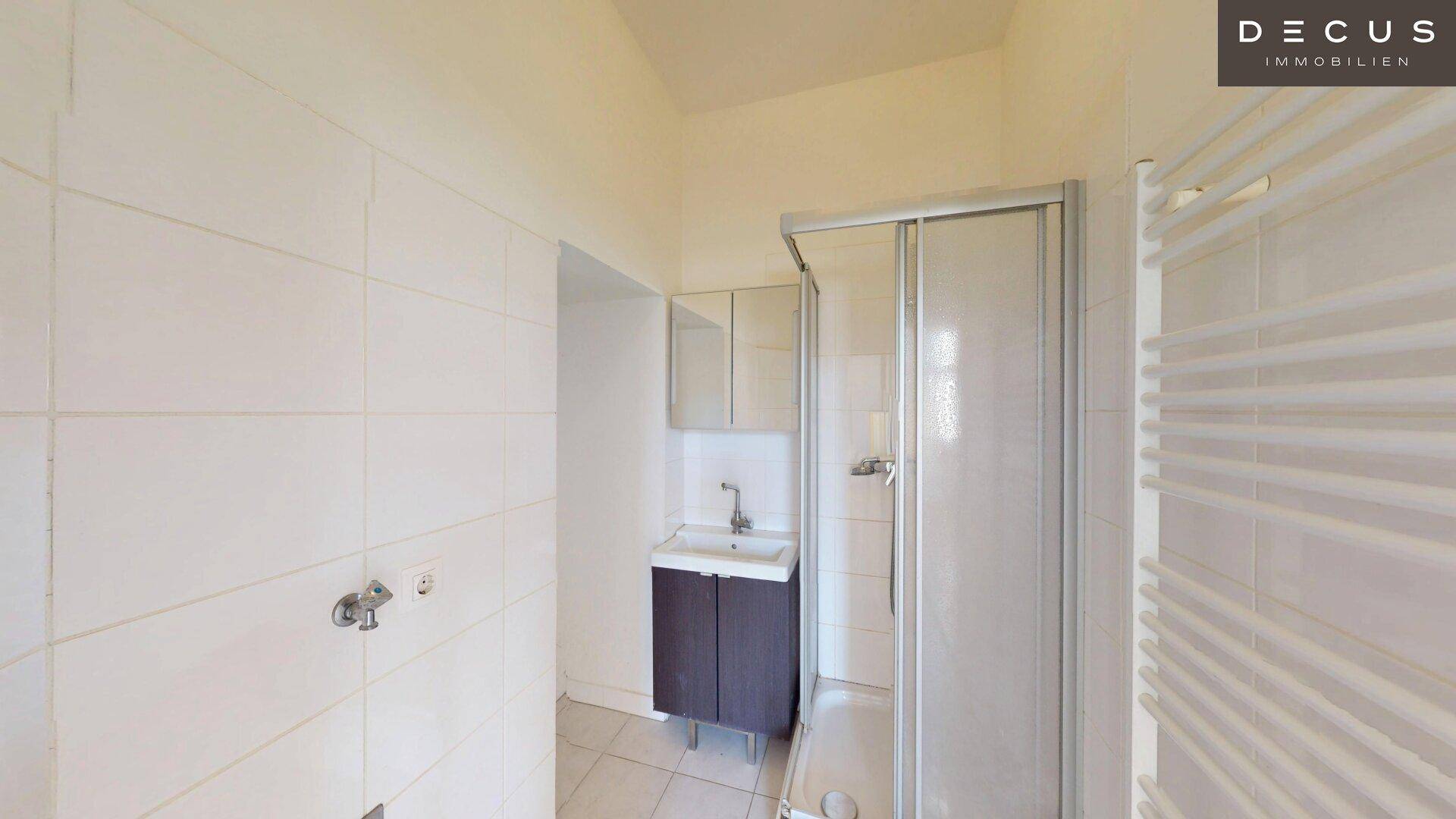 Funktionales Badezimmer mit Duschkabine, Waschbecken und weiß gefliesten Wänden.