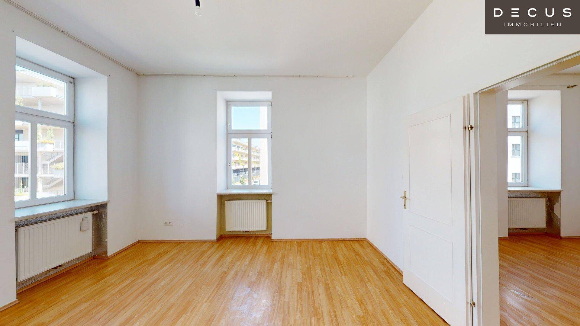 Geräumiges, helles Zimmer mit Holzfußboden und weiß gestrichenen Wänden, bereit zur Einrichtung.