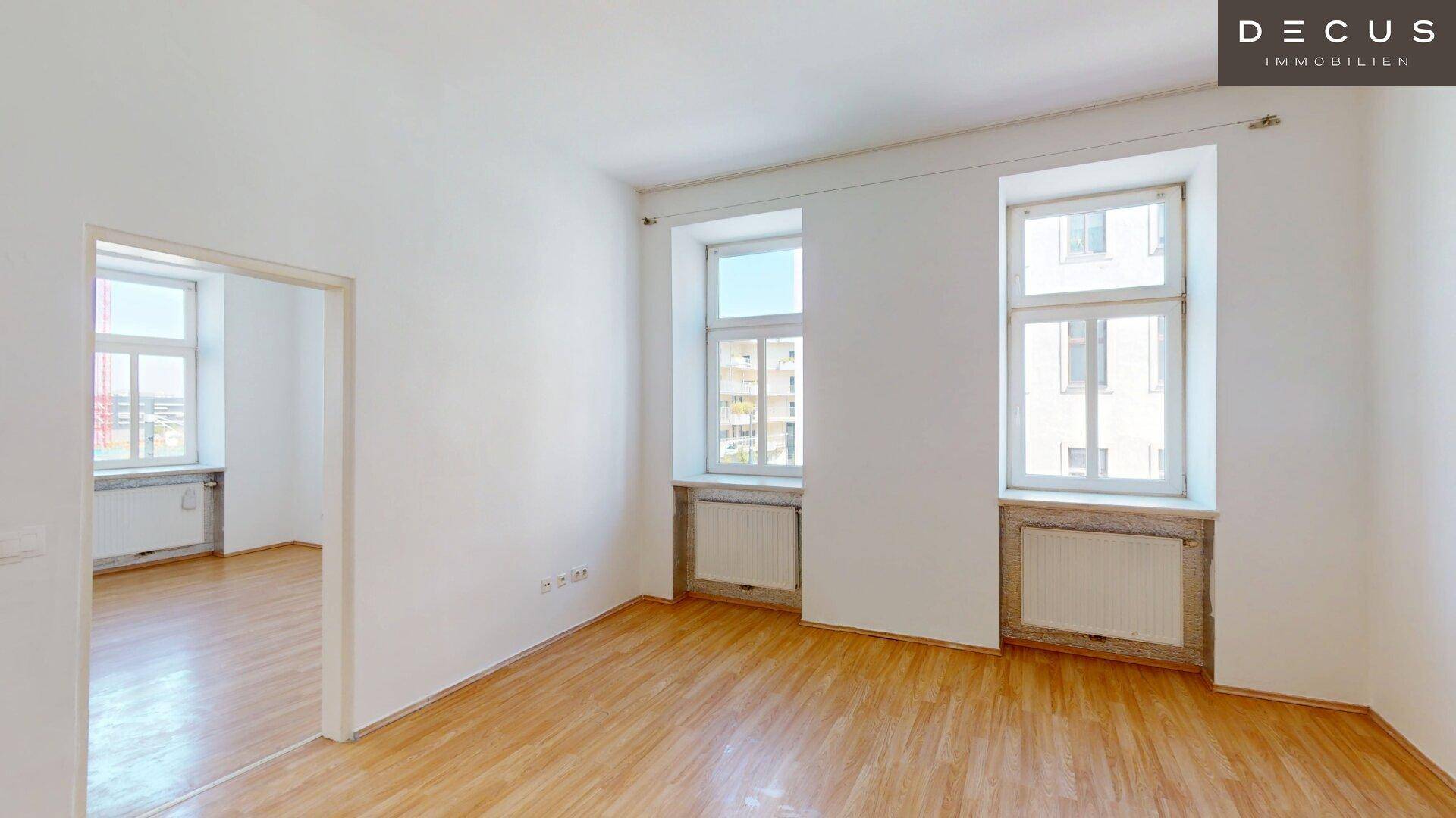Geräumiges, helles Zimmer mit Holzfußboden und mehreren Fenstern, die eine gute Belichtung bieten.