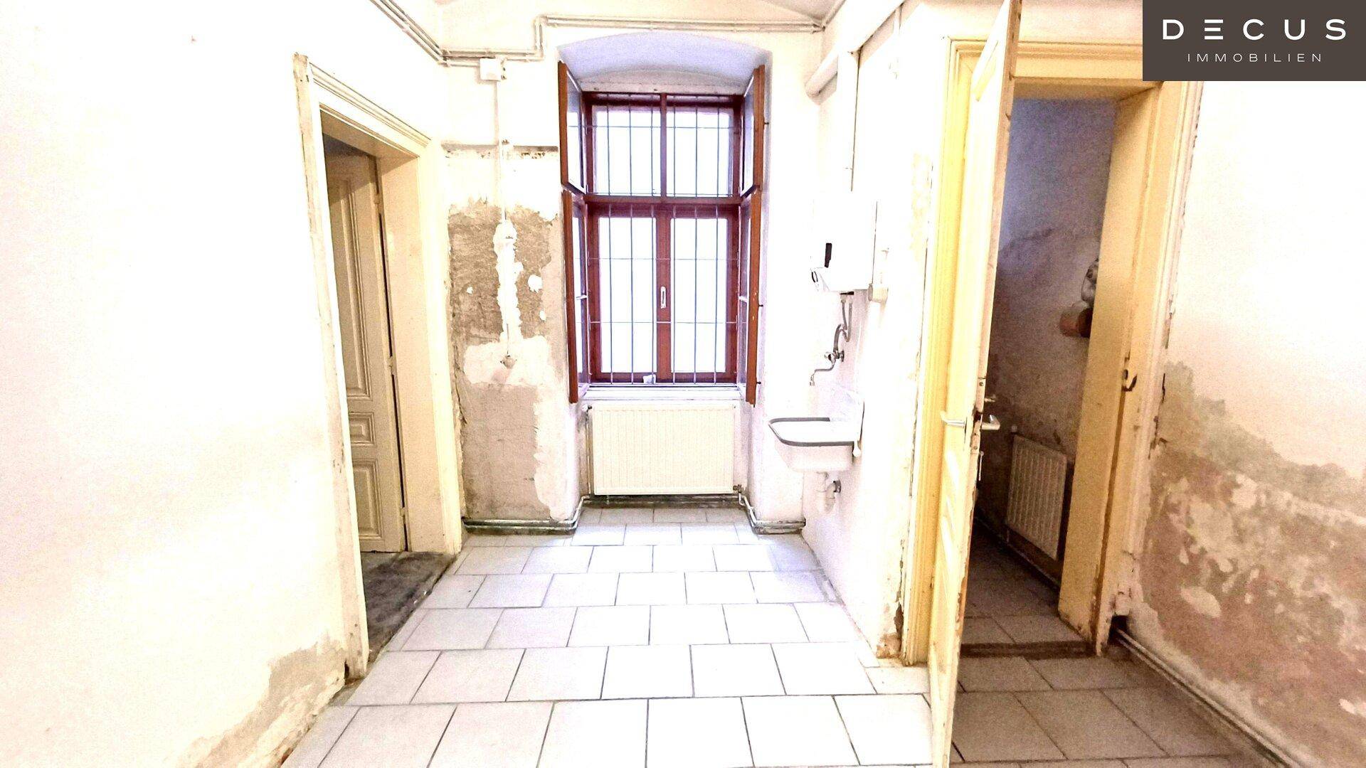 Flur oder Hauswirtschaftsraum mit Fliesenboden, einem alten Fenster und einem Waschbecken.