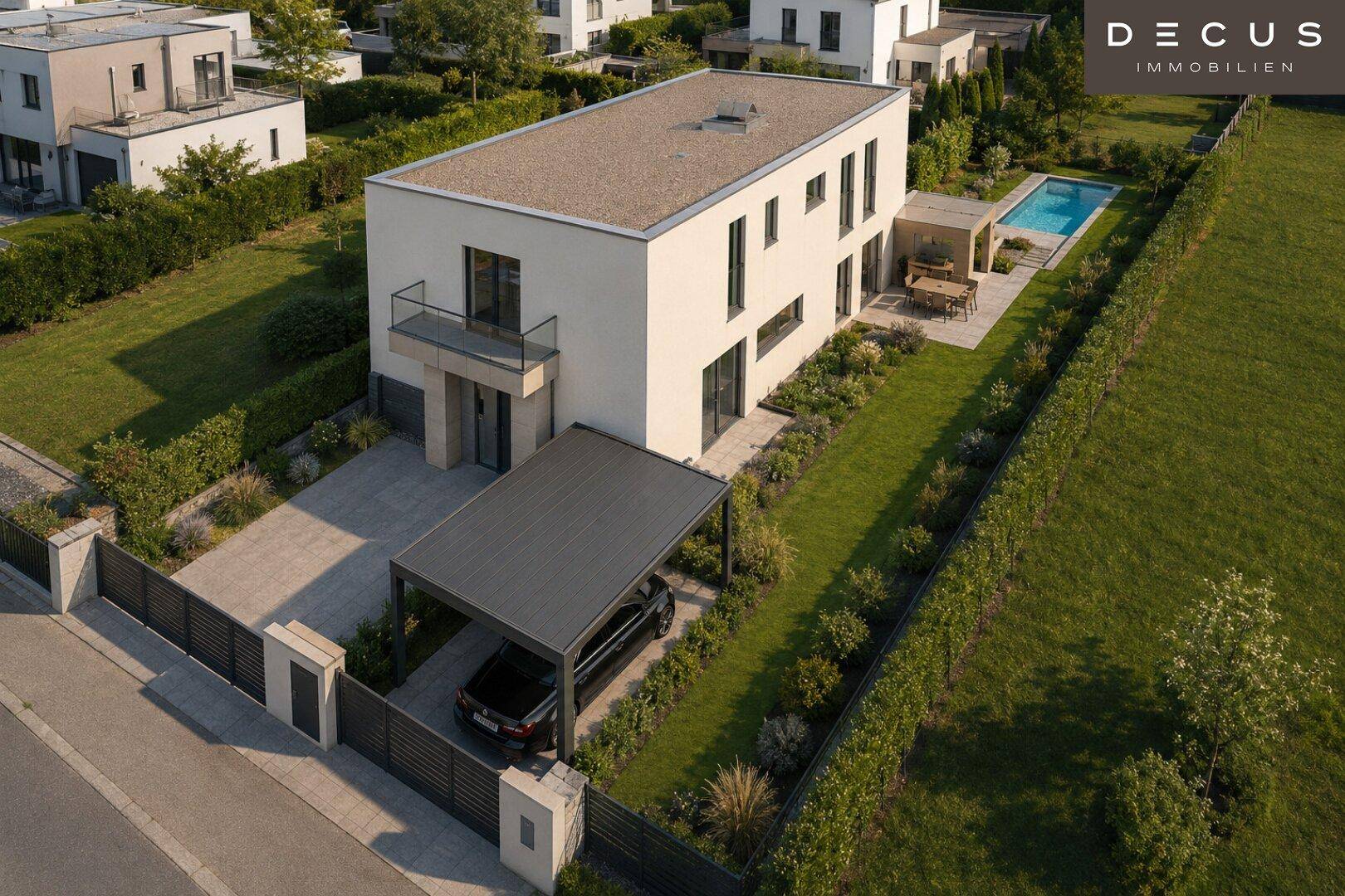 Luftaufnahme einer modernen Wohnanlage mit Einfamilienhaus, Garten, Pool und Carport.