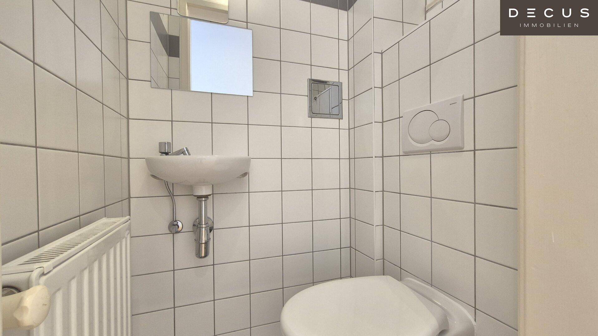Kleines Gäste-WC mit Waschbecken, Toilette und weißen Fliesen, funktional und sauber.