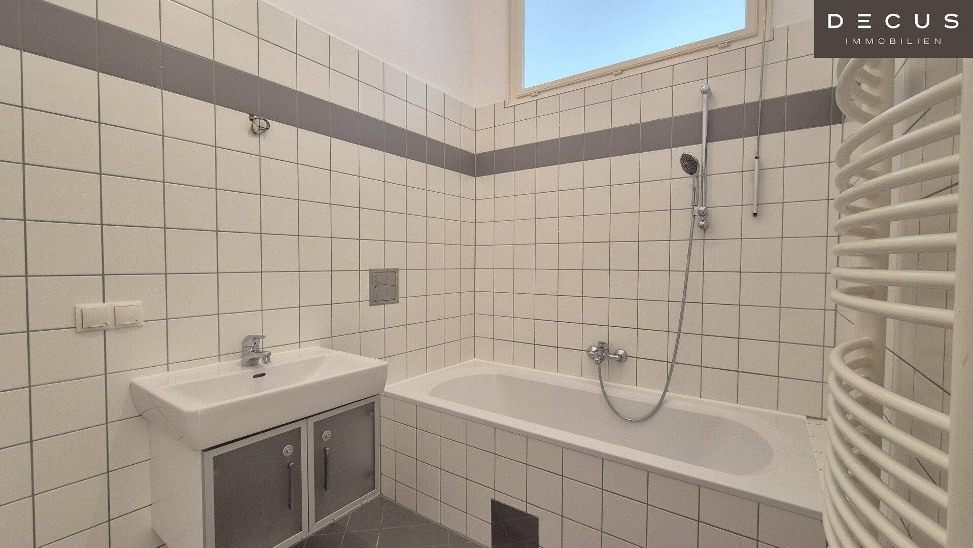 Gefliestes Badezimmer mit Badewanne, Dusche und Handtuchheizkörper, ausgestattet mit einem Fenster.
