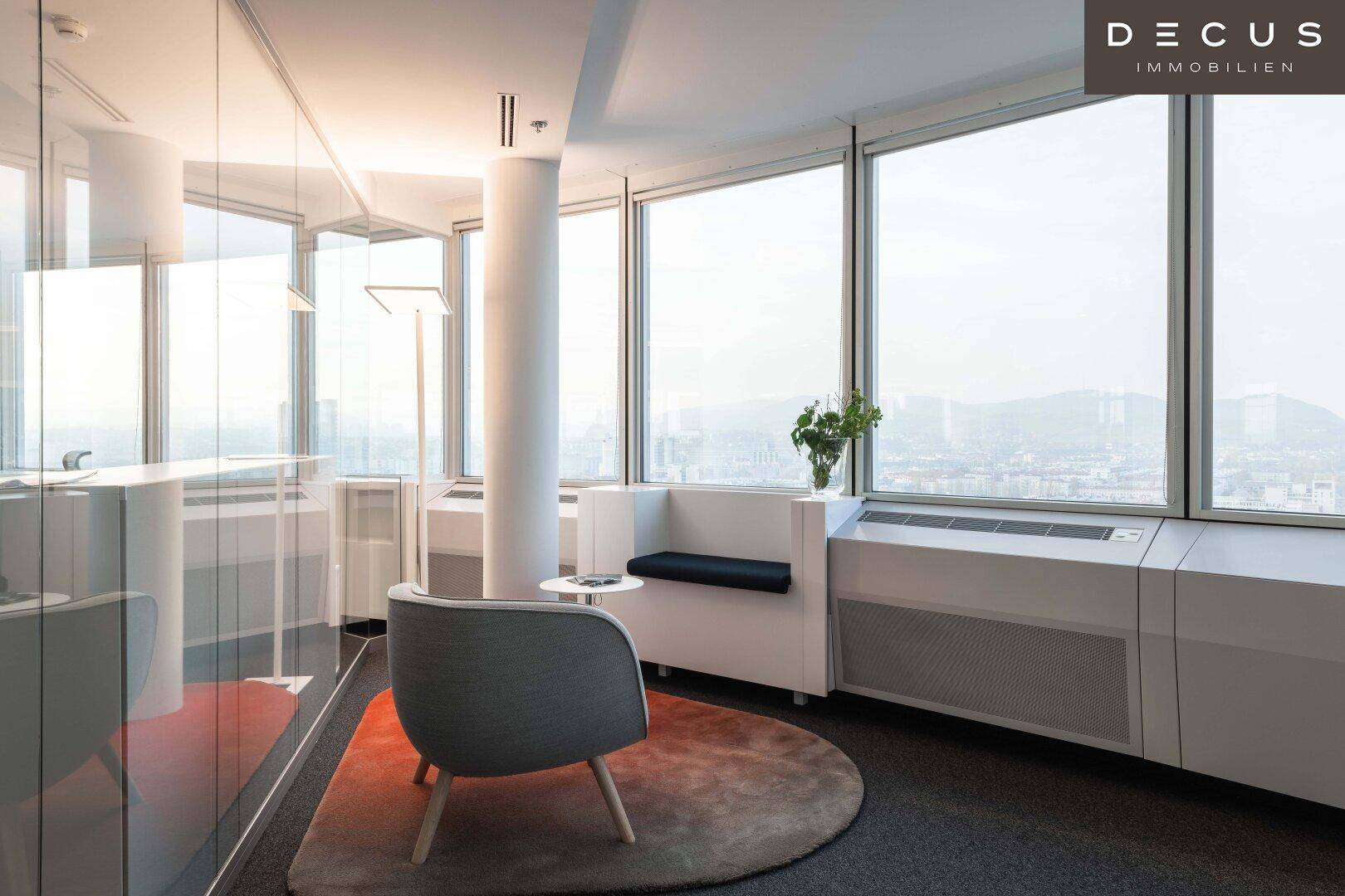 Modernes Büro mit großen Fenstern, die einen weiten Blick über die Stadt bieten und viel Tageslicht hereinlassen.