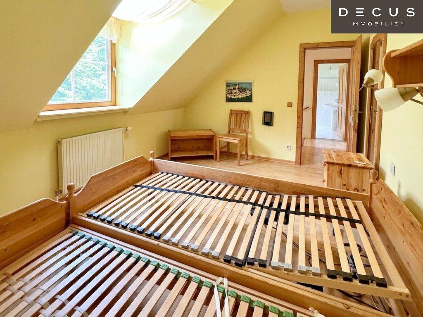 Geräumiges Schlafzimmer im Dachgeschoss mit zwei Bettgestellen und gelben Wänden.