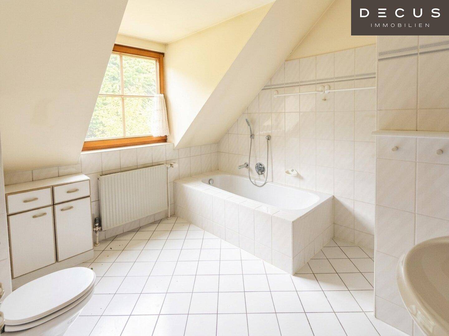 Helles Badezimmer im Dachgeschoss mit Badewanne, WC und Fliesenboden.