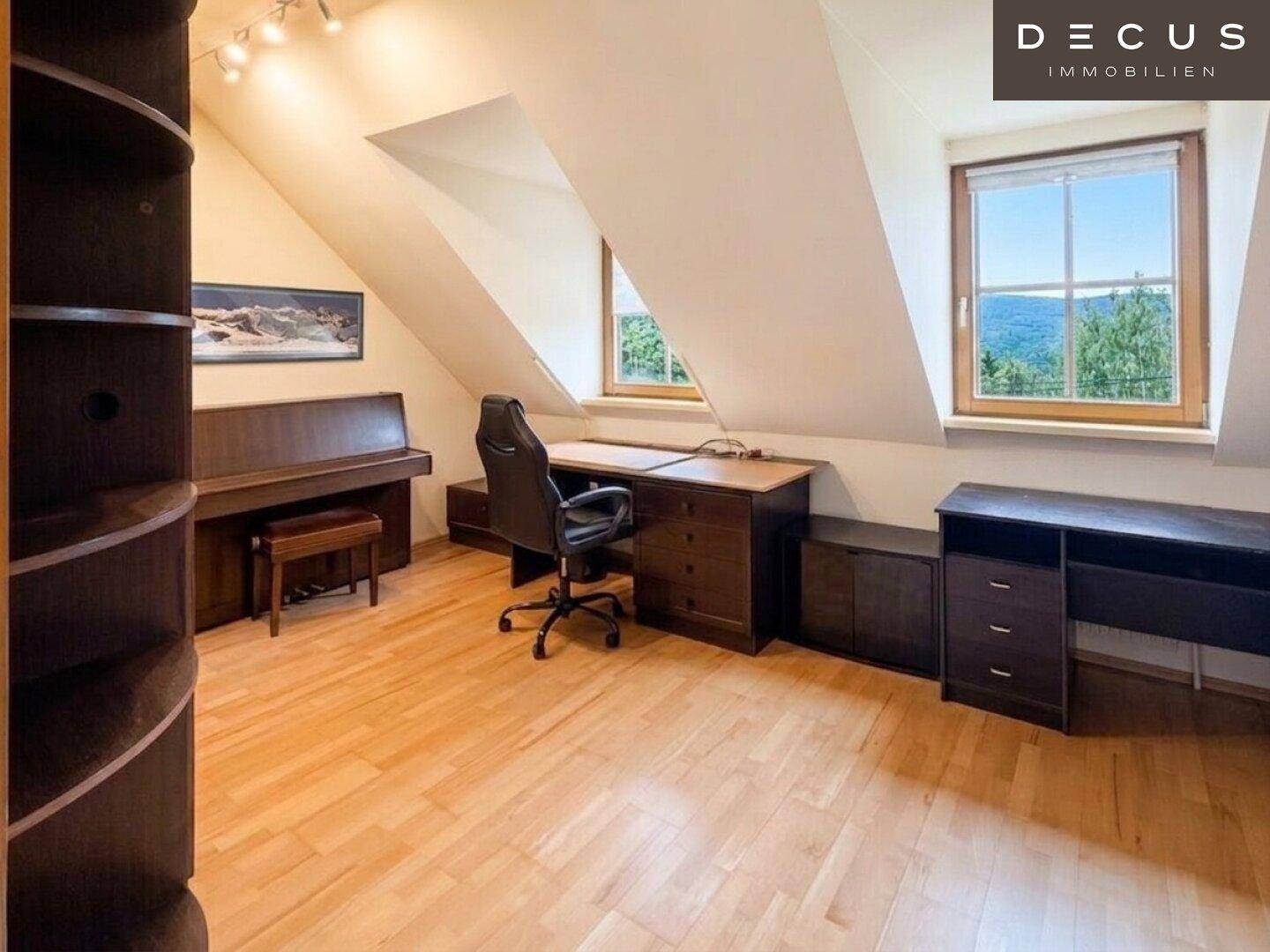 Helles Arbeitszimmer im Dachgeschoss mit Schreibtisch, Klavier und Blick ins Grüne.