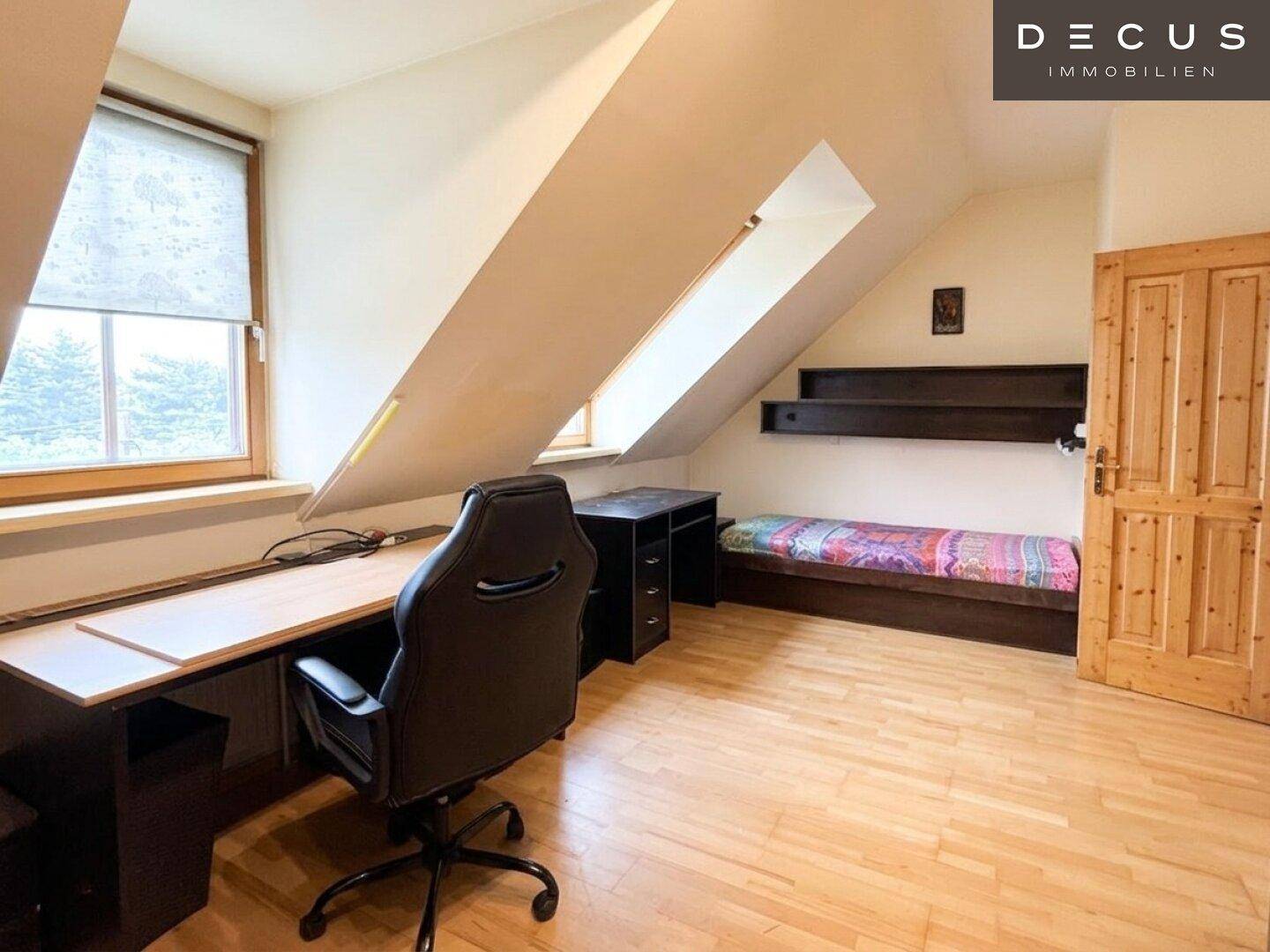 Schlafzimmer im Dachgeschoss mit Schreibtisch, Einzelbett und Dachschrägen.