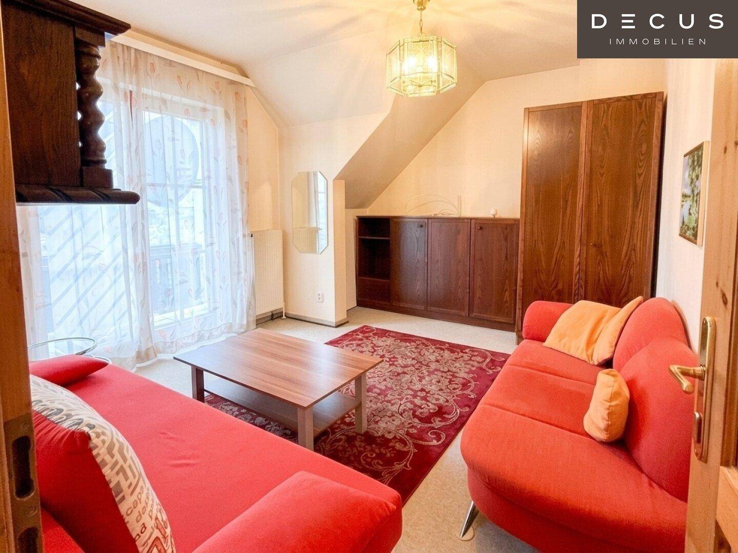 Gemütlicher Wohnraum im Dachgeschoss mit Schrägen, Sofa und Blick nach draußen.