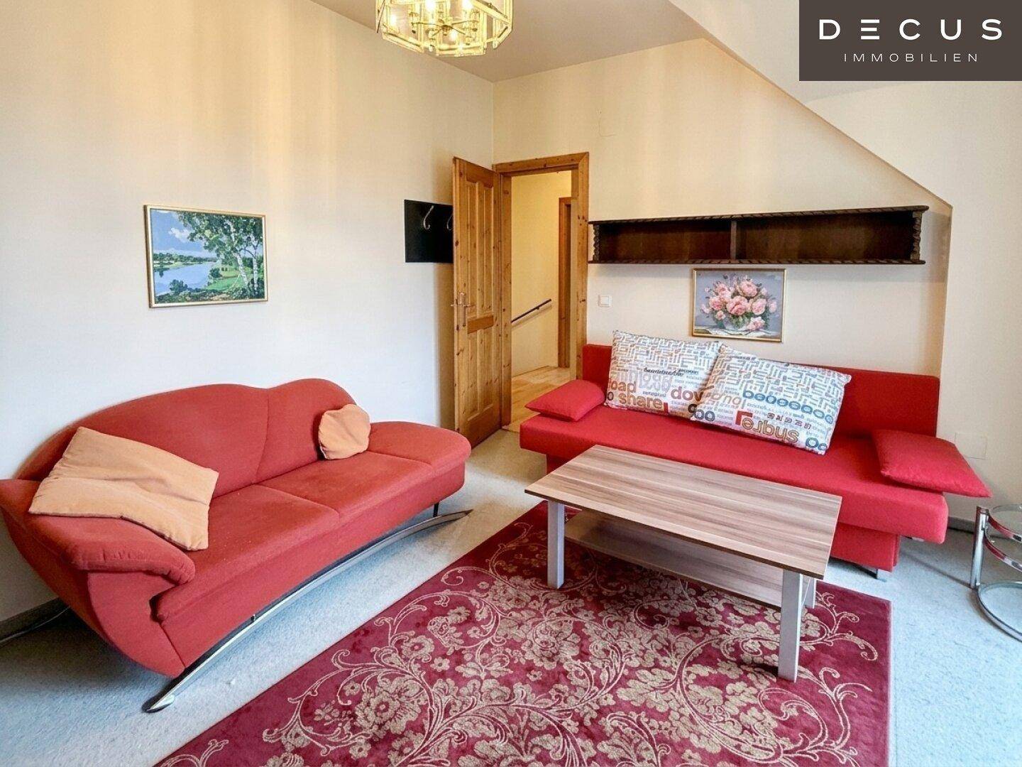 Heller Wohnbereich im Dachgeschoss mit bequemen Sofas und Teppichboden.
