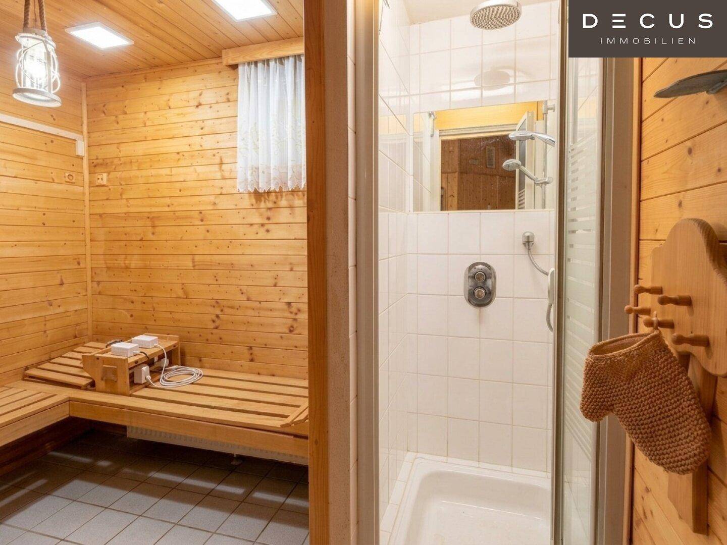 Badezimmer mit Duschkabine und angrenzender Holzsauna für Entspannung.