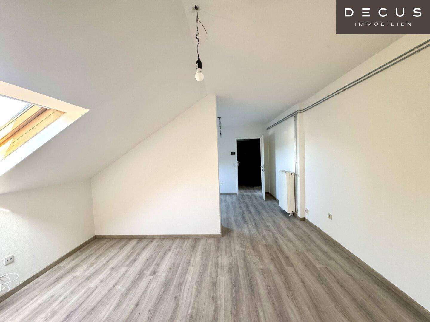 Geräumiger Dachraum mit Laminatboden, weißen Wänden und einem großen Dachfenster.
