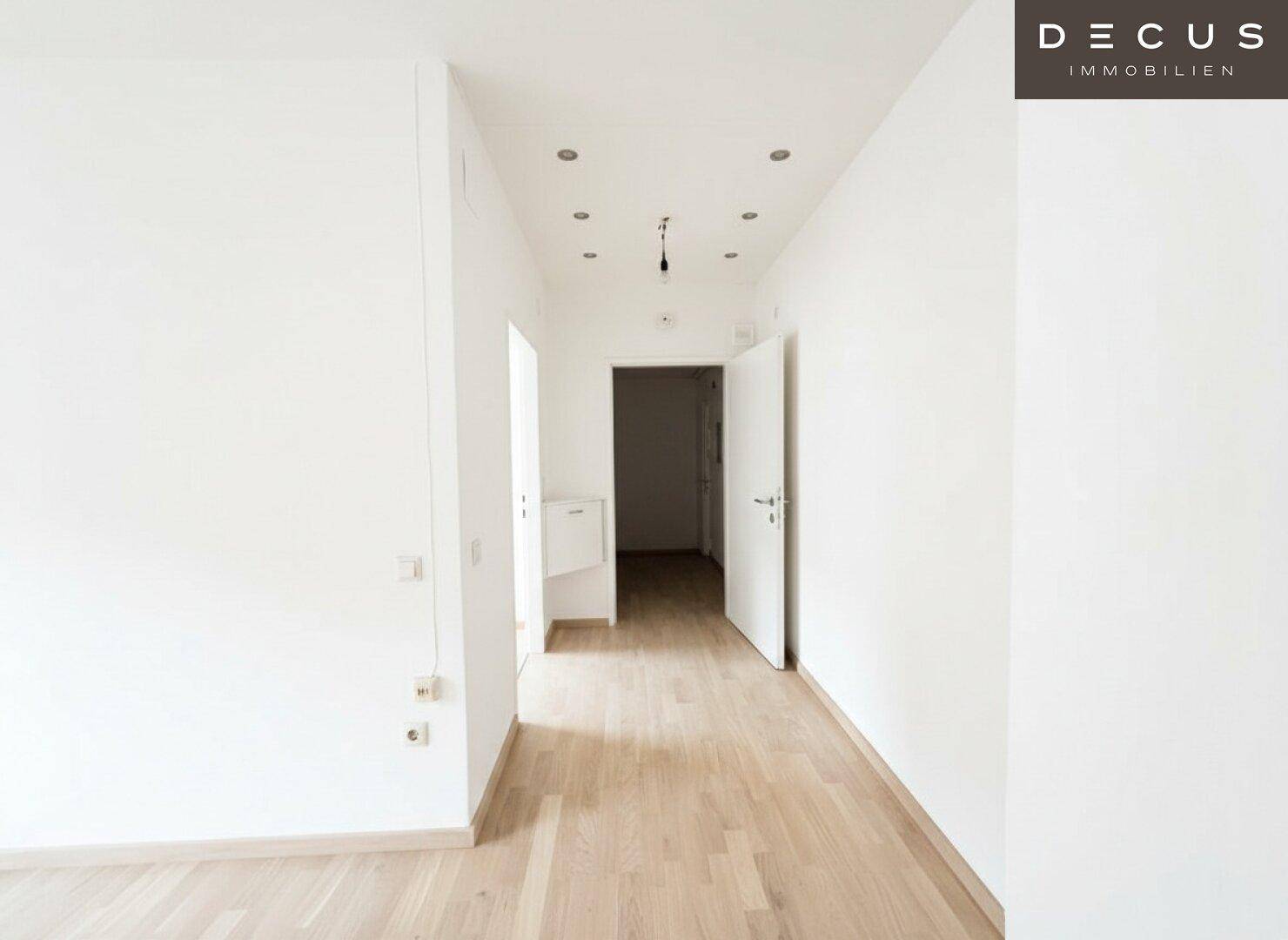 Heller Flur mit hellem Laminatboden und Einbaustrahlern, der zu weiteren Räumen führt.
