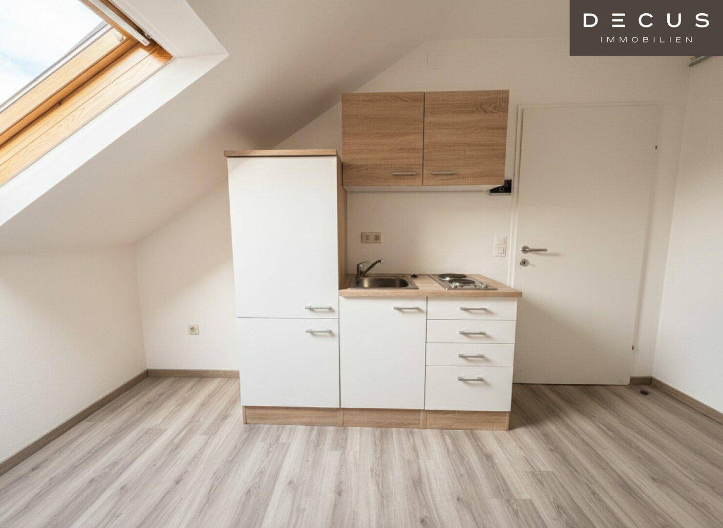 Kleine Küchenzeile in einem Dachzimmer mit Dachfenster und Laminatboden, ideal für Singles.