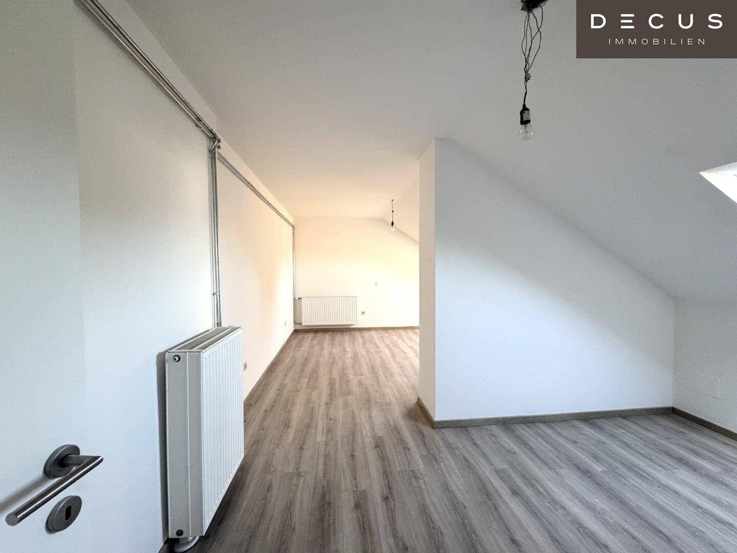 Heller Raum mit Laminatboden, weißen Wänden und Dachschräge, ideal für flexible Nutzung.