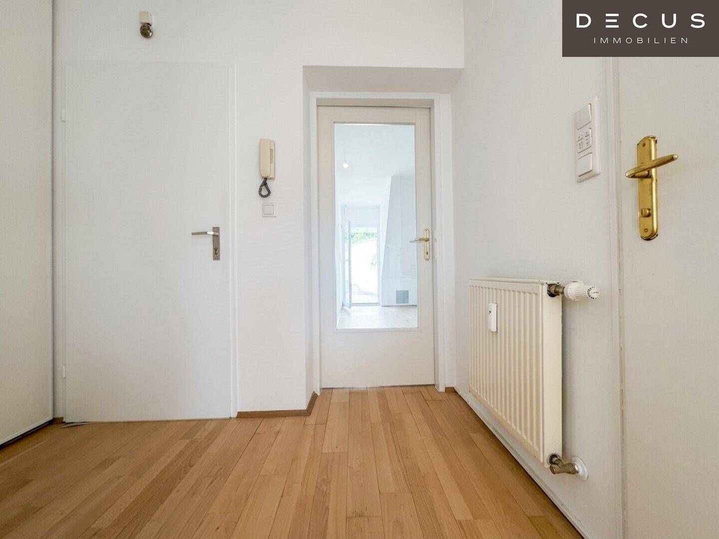 Eingangsbereich mit Holzboden und weißer Tür, bietet Zugang zu den Wohnräumen.