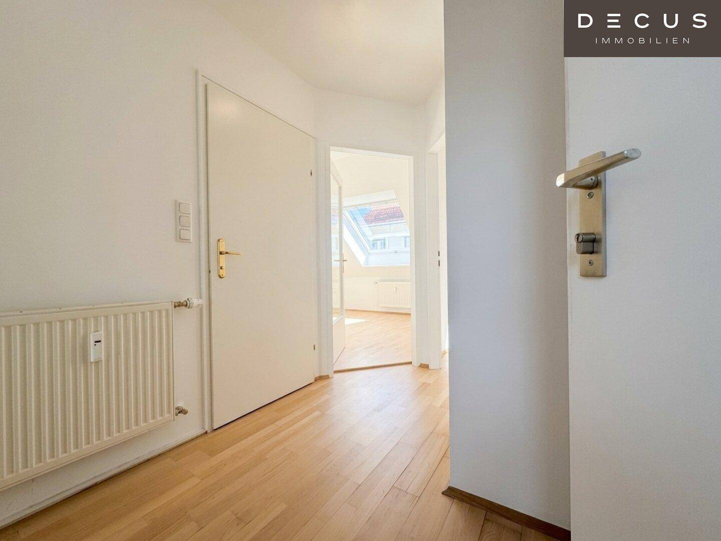Heller Flur mit Holzboden und weißen Türen, führt zu weiteren Räumen der Wohnung.
