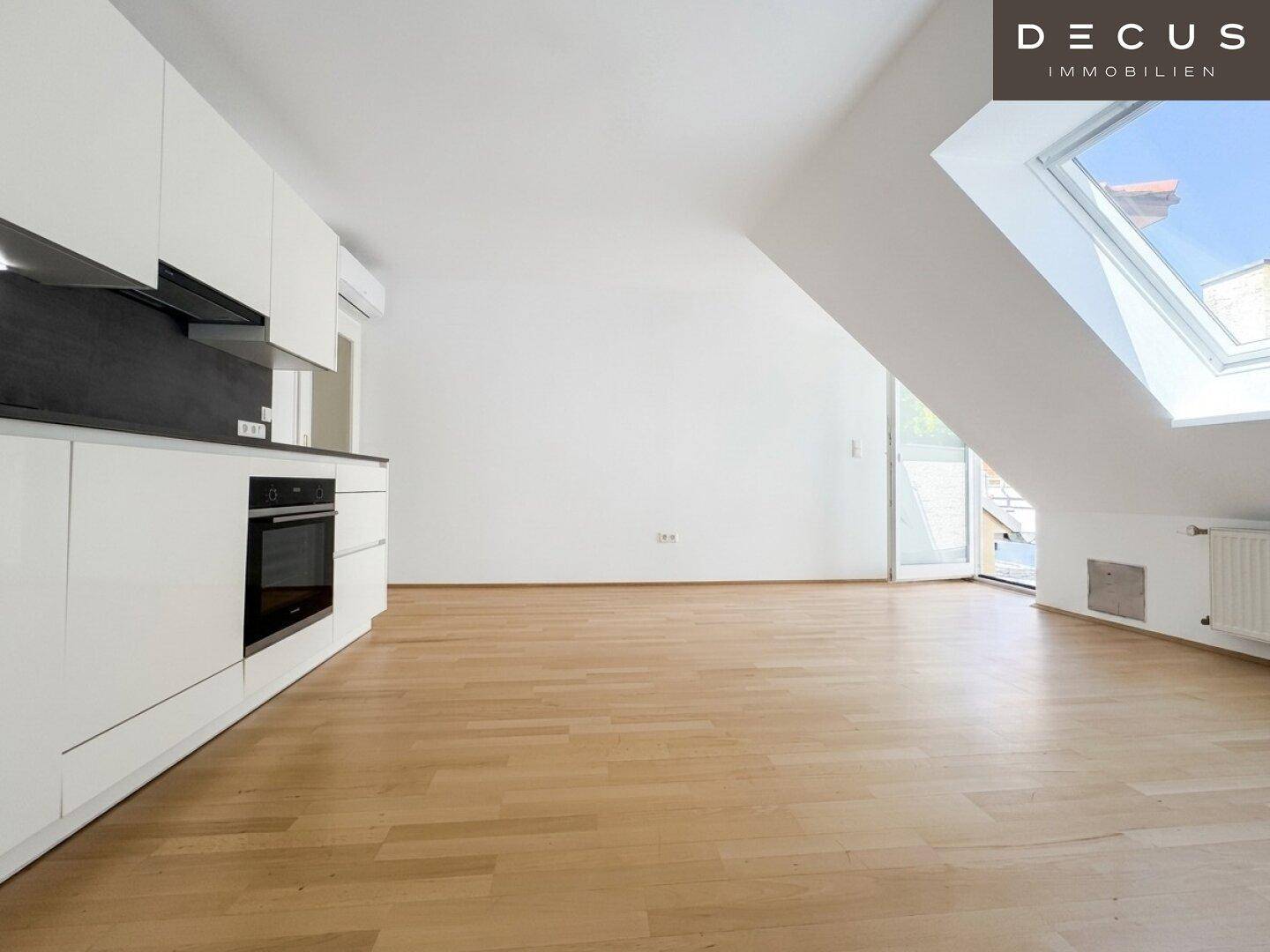Offener Küchenbereich im Dachgeschoss mit Holzboden und Dachfenster, bietet Zugang nach draußen.