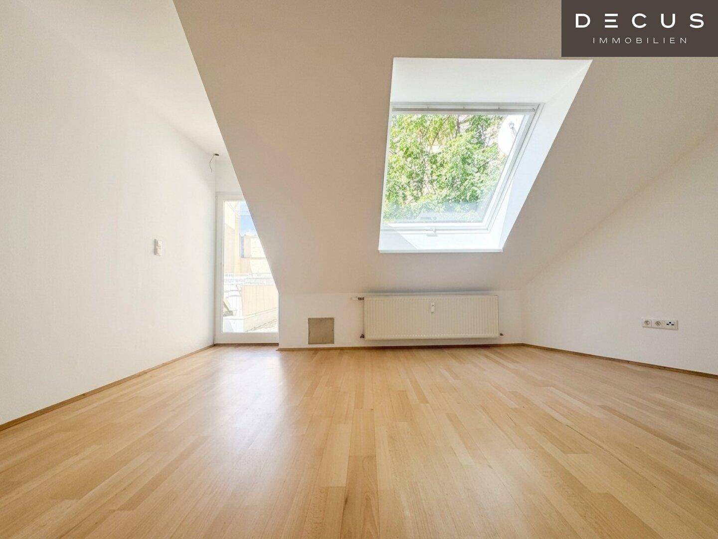 Geräumiger Essbereich im Dachgeschoss mit Holzboden und großem Dachfenster, unmöbliert.