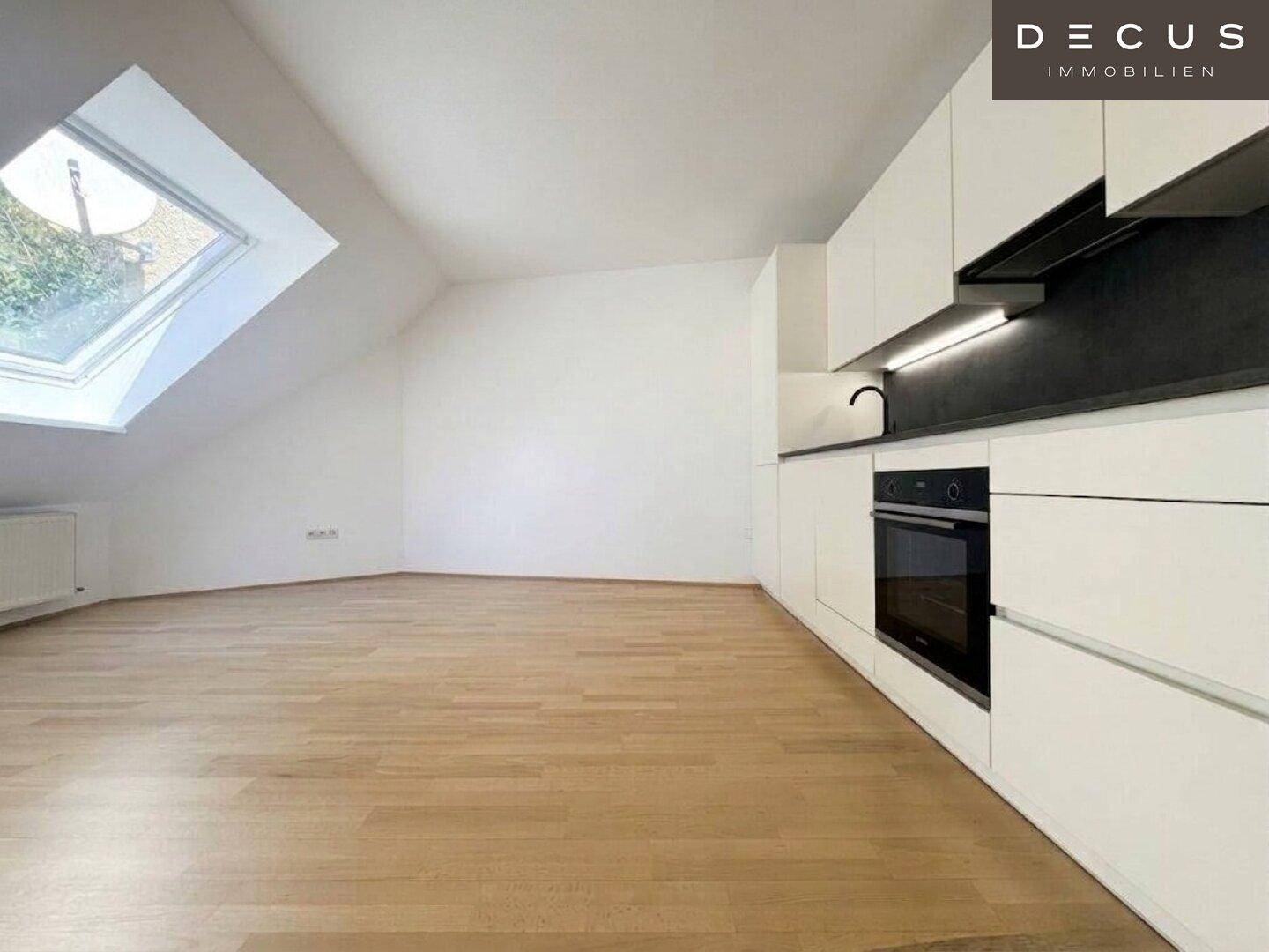 Moderne Küchenzeile im Dachgeschoss mit weißen Schränken und Holzboden, hell und funktional.