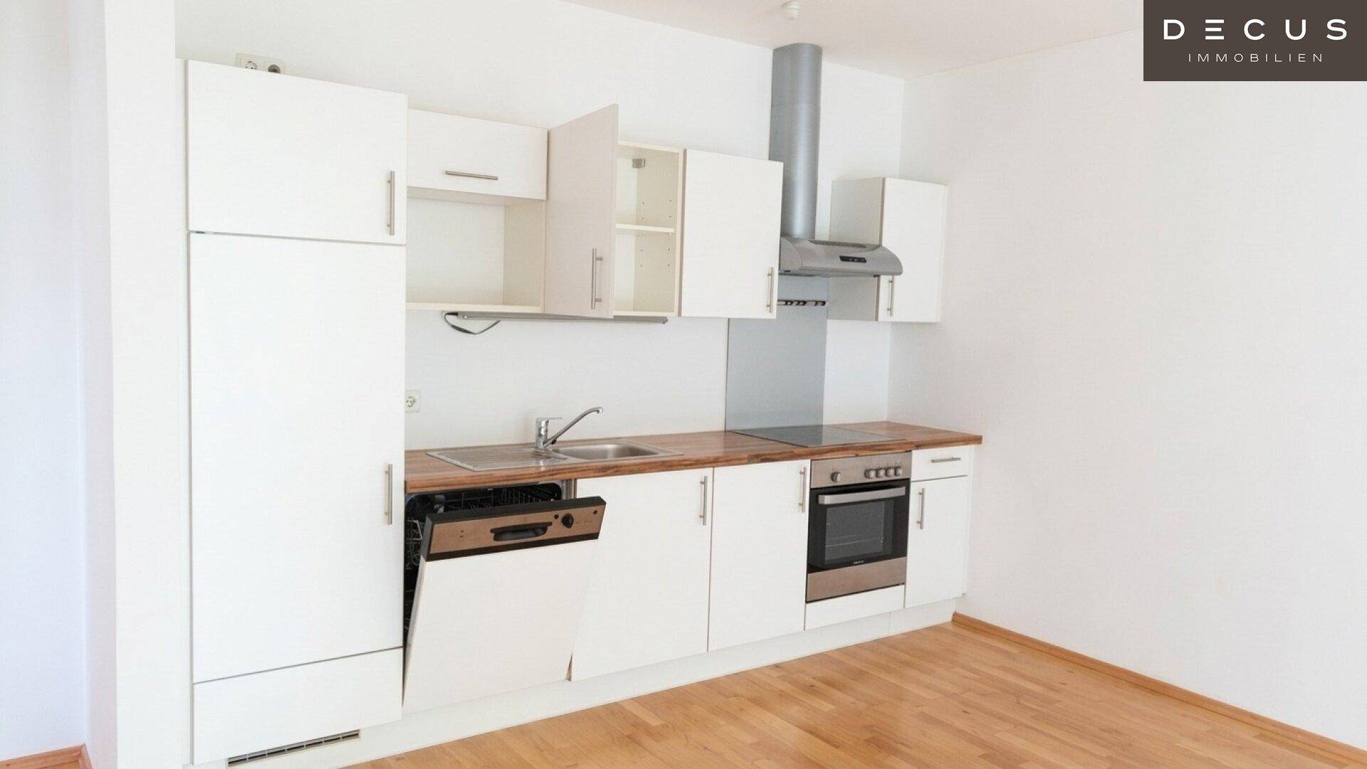 Helle Einbauküche mit weißen Schränken, Holz-Arbeitsplatte und modernen Elektrogeräten.