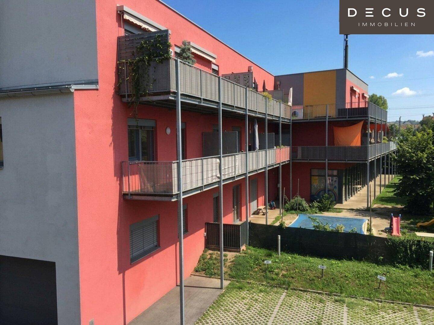 Ansicht der Balkone des Wohngebäudes mit Blick auf einen kleinen Spielplatzbereich im Hintergrund.