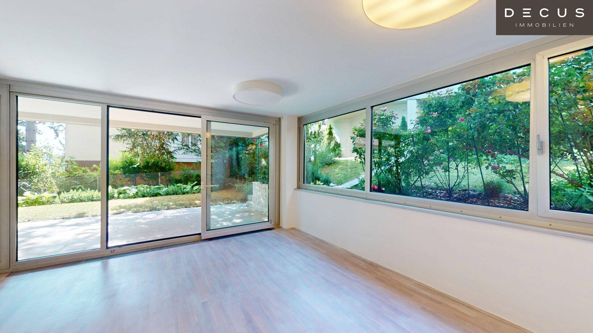 Heller Wohnraum mit großen Fenstern und Schiebetüren, die einen direkten Blick in den grünen Garten bieten.