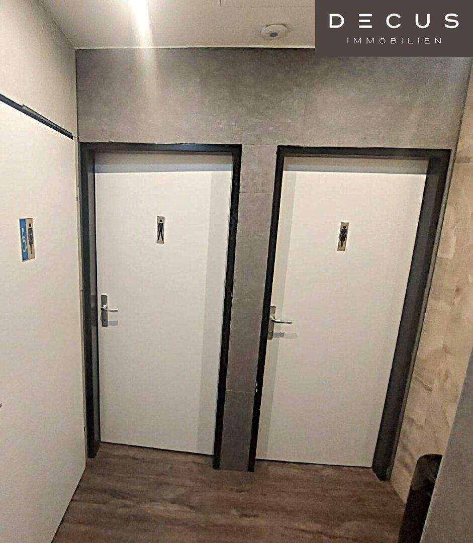 Zwei Türen, die zu den Toiletten führen, mit deutlichen Symbolen für Damen und Herren.