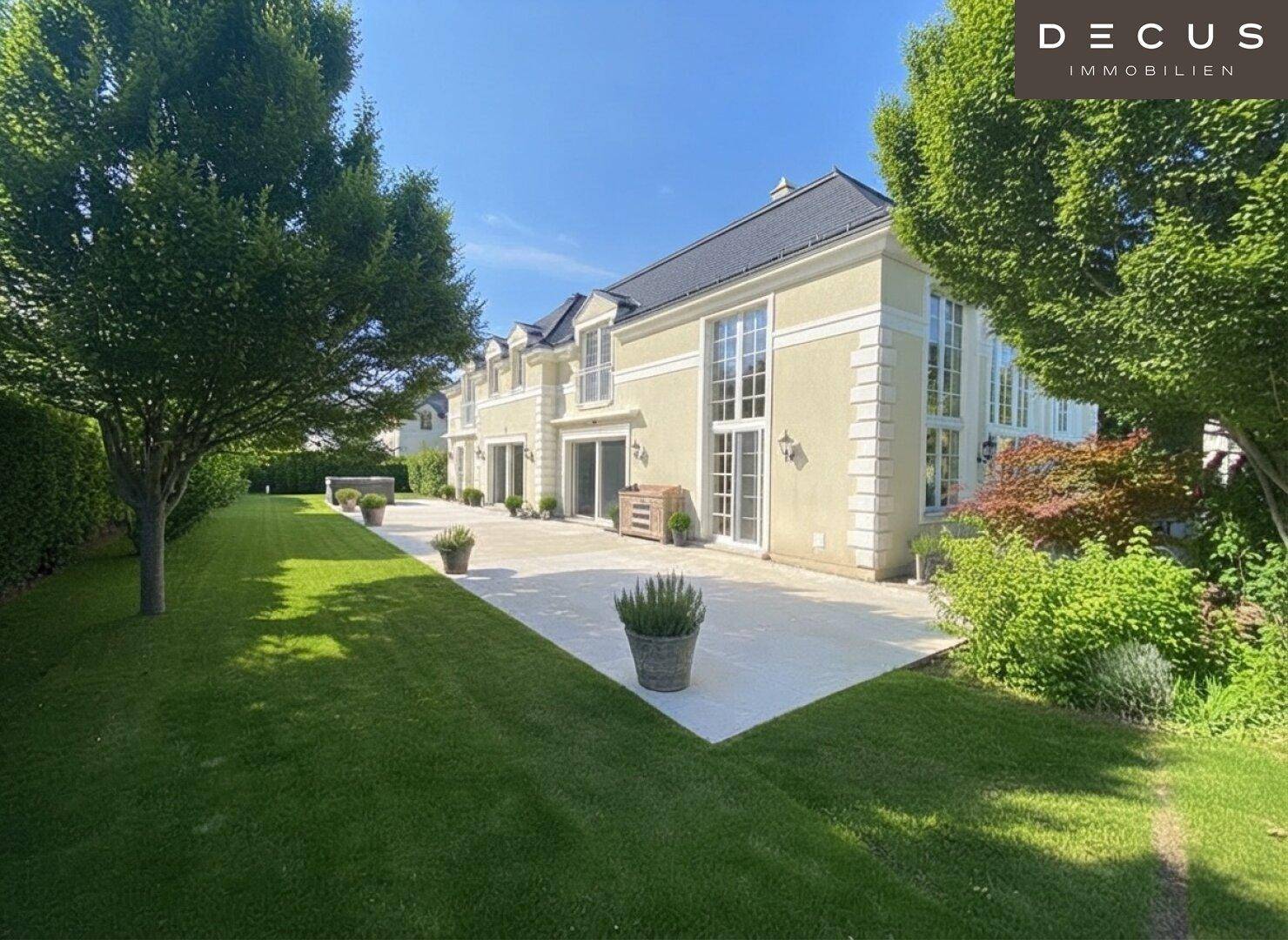 Weitläufiger Garten mit großer Rasenfläche und einer sonnigen Terrasse vor der Villa.