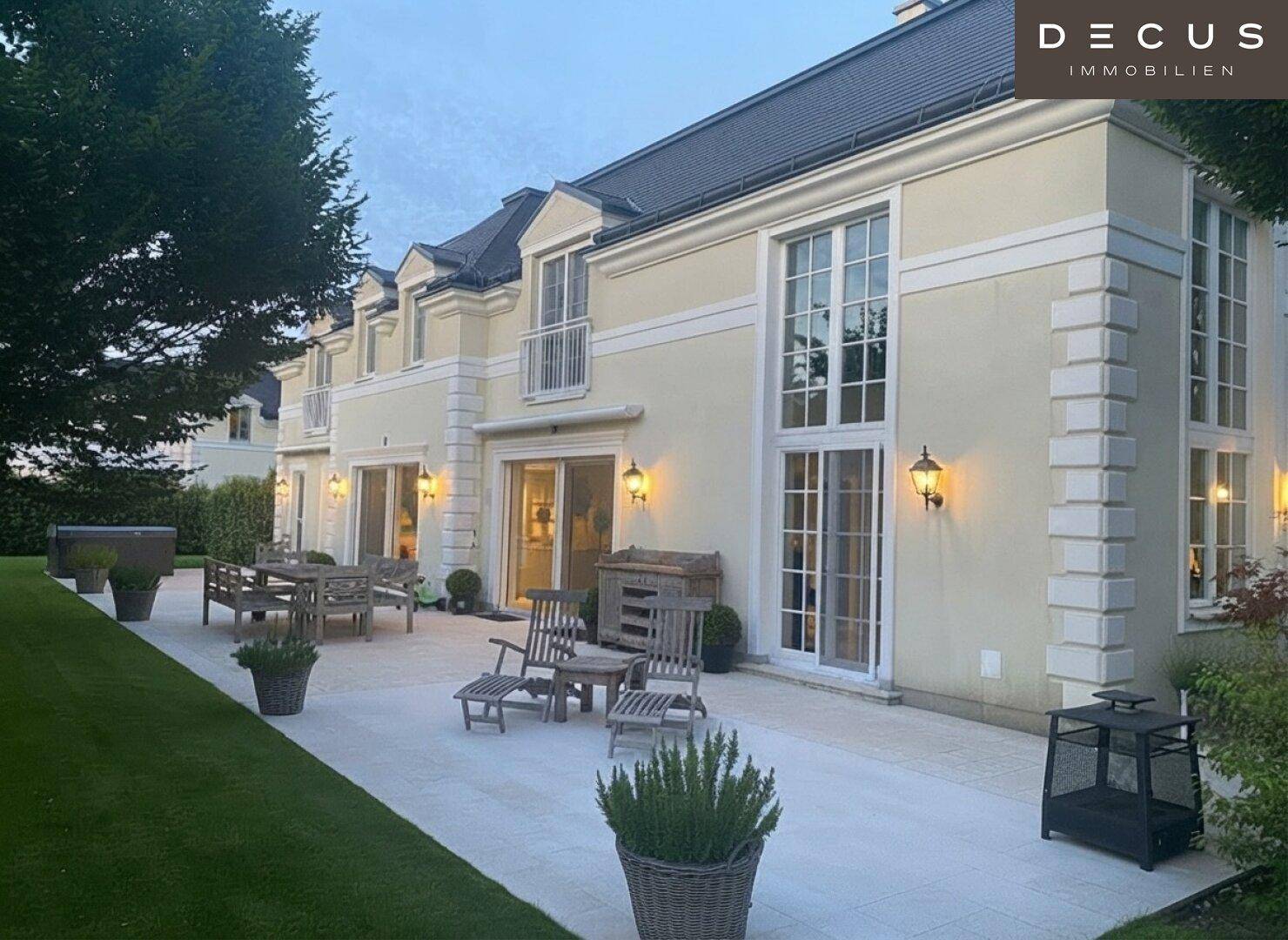 Geräumige Terrasse mit Gartenmöbeln und Rasenfläche, beleuchtet am Abend.