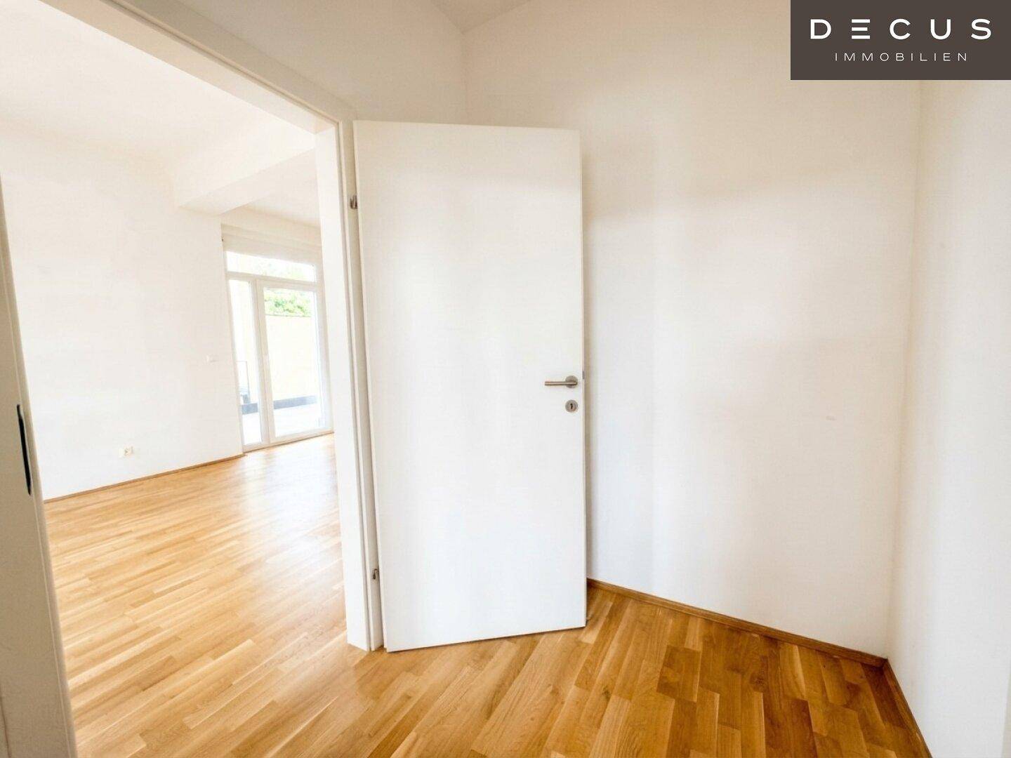 Heller Flur mit Holzboden, der zu weiteren Räumen führt und eine offene Atmosphäre schafft.