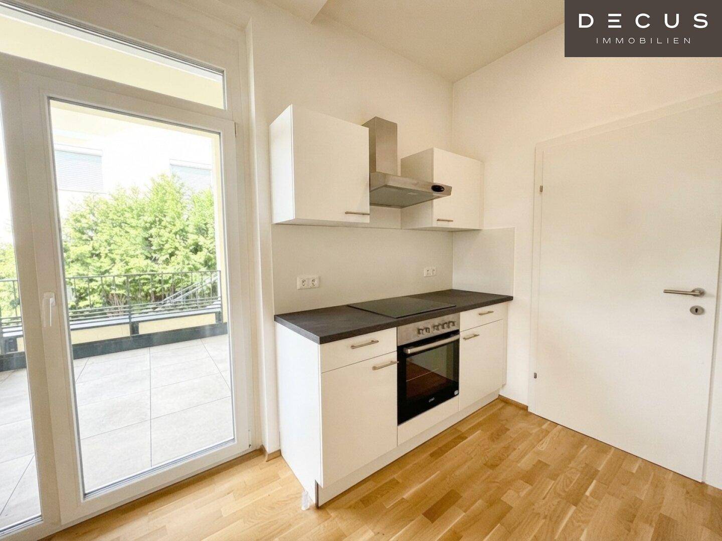 Helle Küchenzeile mit Zugang zu einer großen Terrasse, ausgestattet mit modernen Geräten.