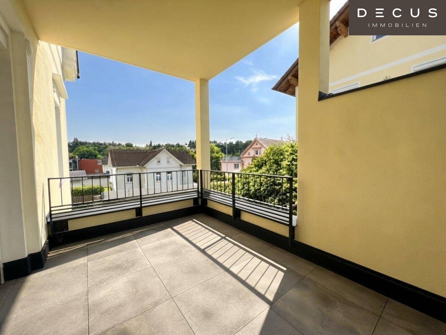 Großer, sonniger Balkon mit Fliesenboden und weitem Blick über die Nachbarschaft.