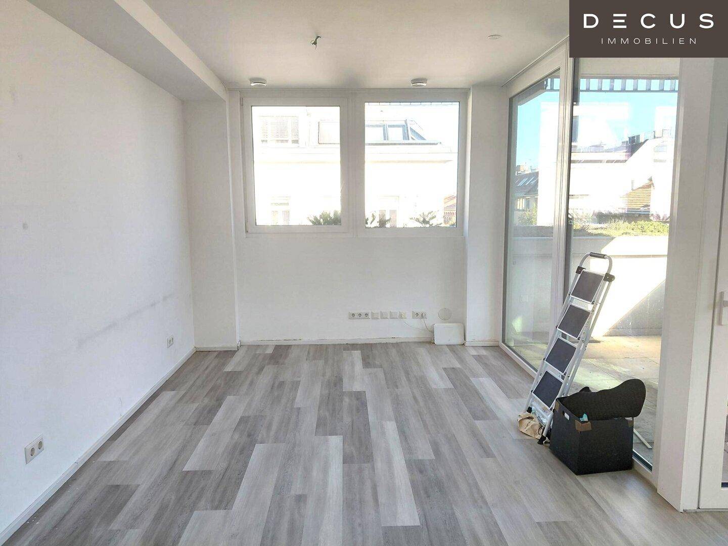 Heller, leerer Raum mit großen Fenstern und Zugang zu einem Außenbereich, ideal für Wohnzwecke.