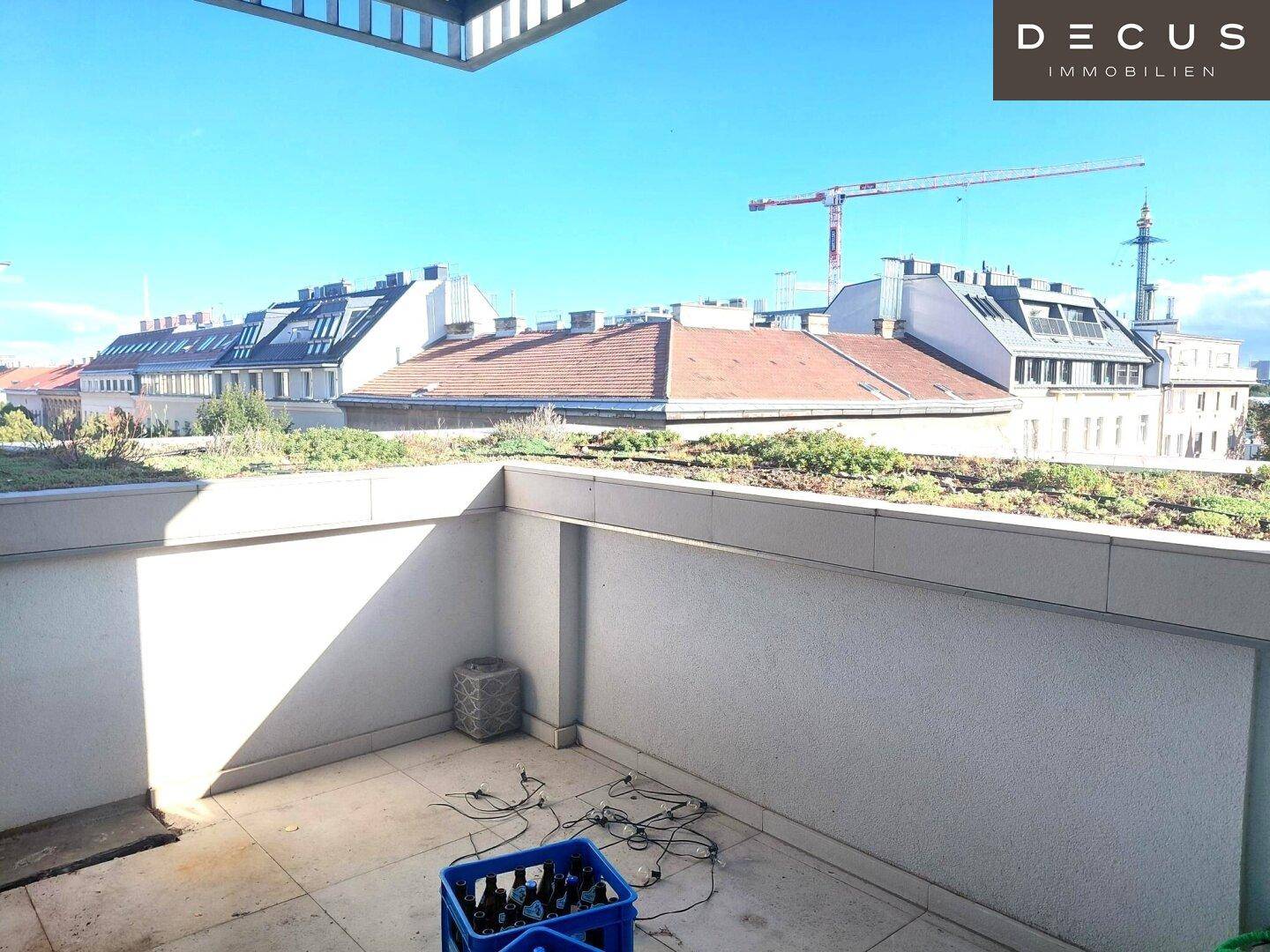 Sonniger Außenbereich mit Blick auf die Dächer der Stadt und einen Baukran im Hintergrund.