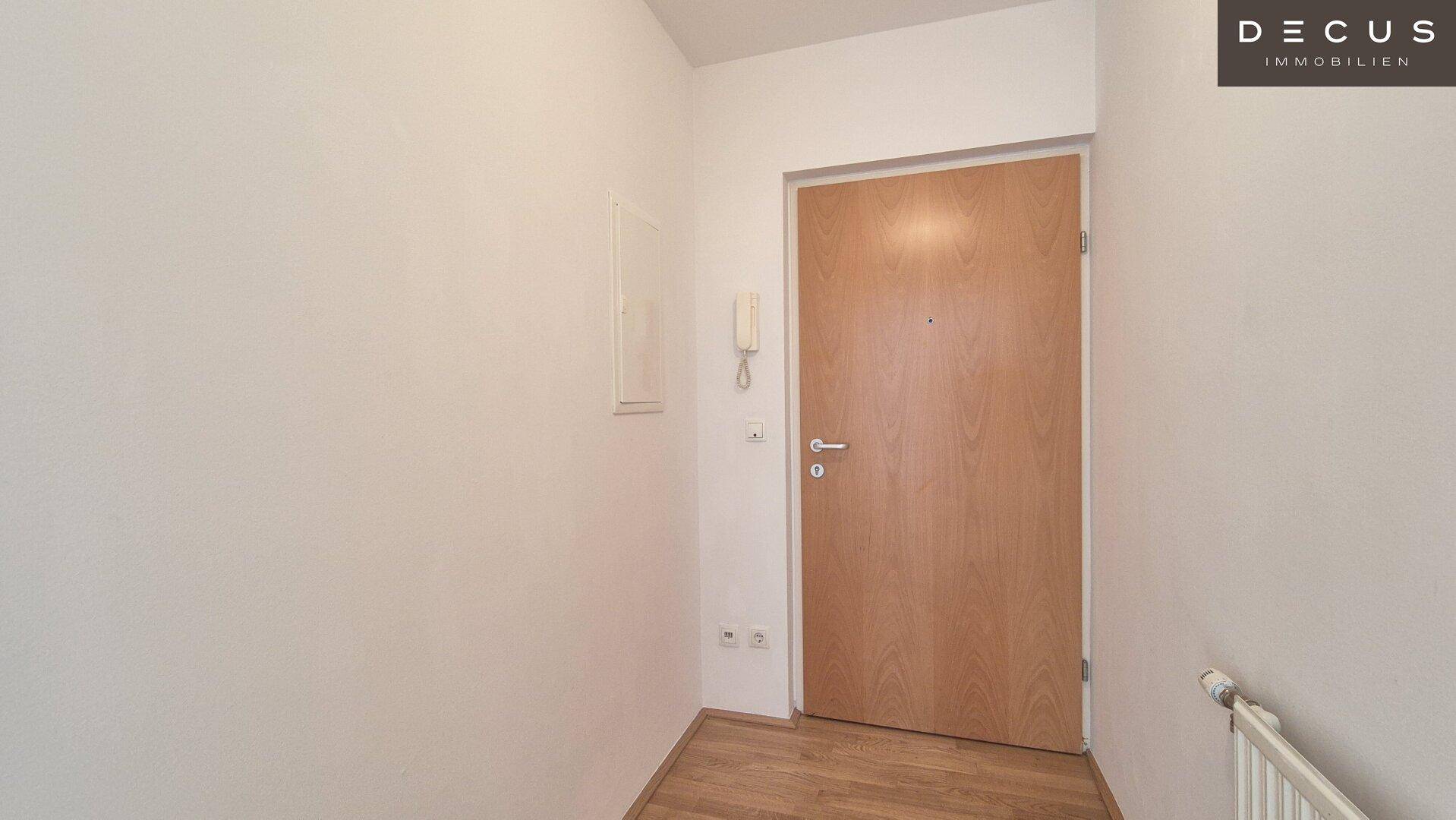 Eingangsbereich mit Holztür, Parkettboden und Gegensprechanlage, hell und einladend.