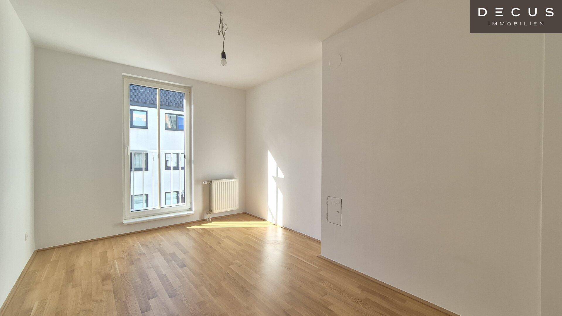 Lichtdurchfluteter Raum mit Parkettboden und großem Fenster, ideal als Schlaf- oder Arbeitszimmer.