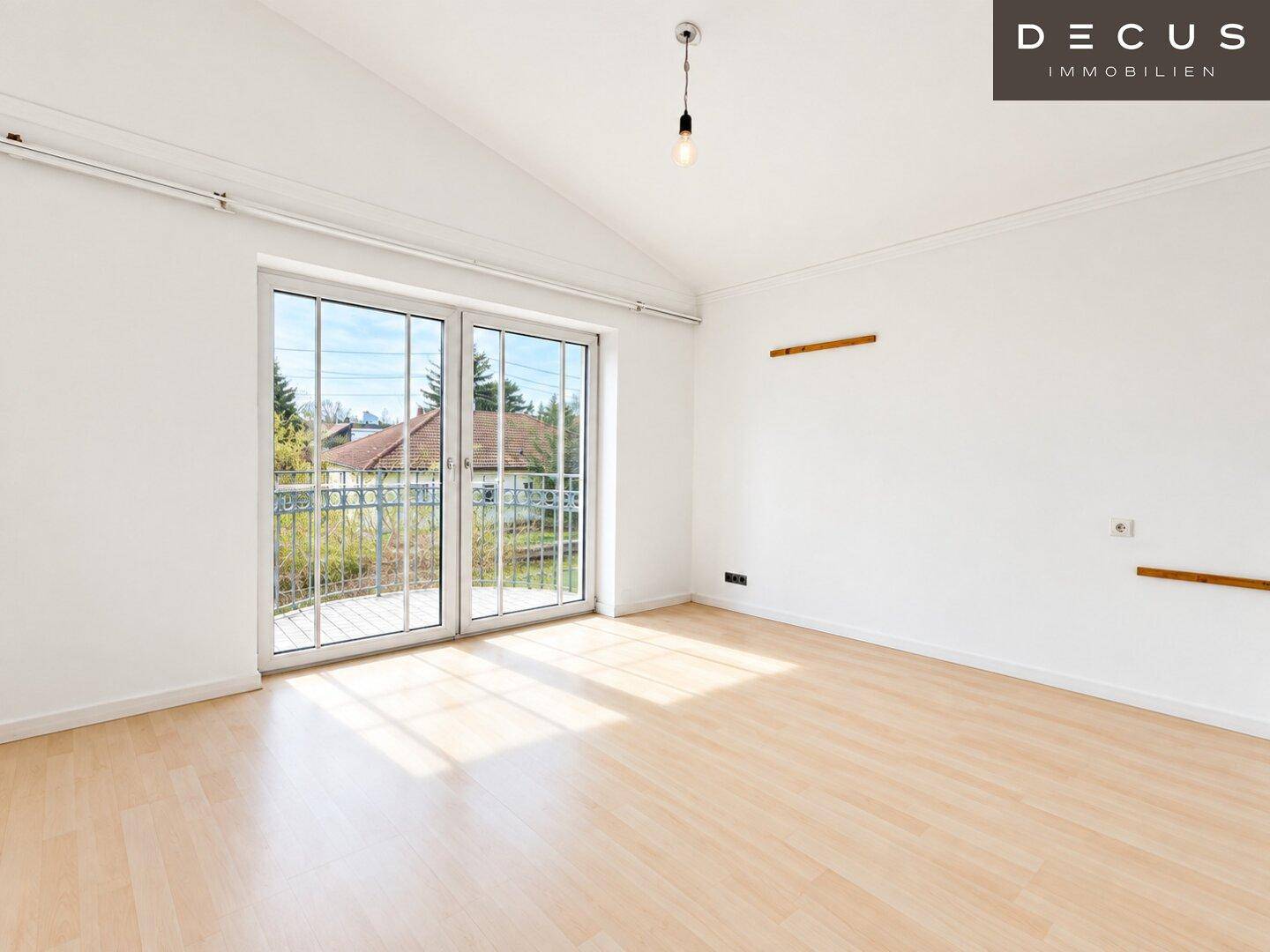 Helles Schlafzimmer mit Laminatboden, Dachschräge und Zugang zu einem Balkon.