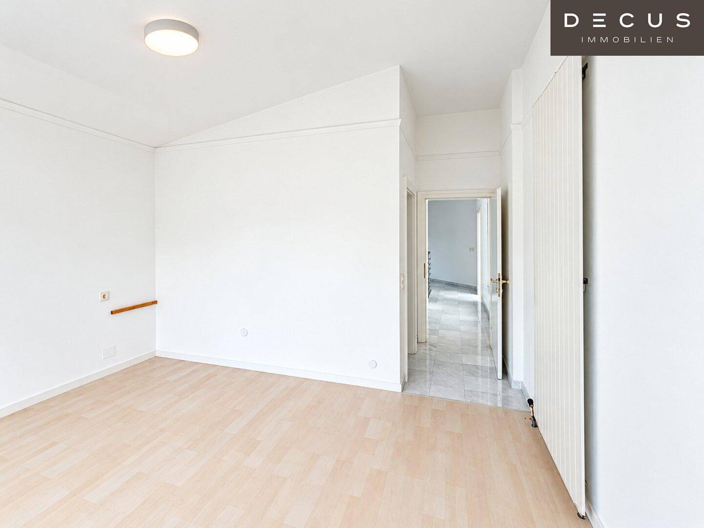 Helles Schlafzimmer mit Laminatboden, Dachschräge und Zugang zum Flur.