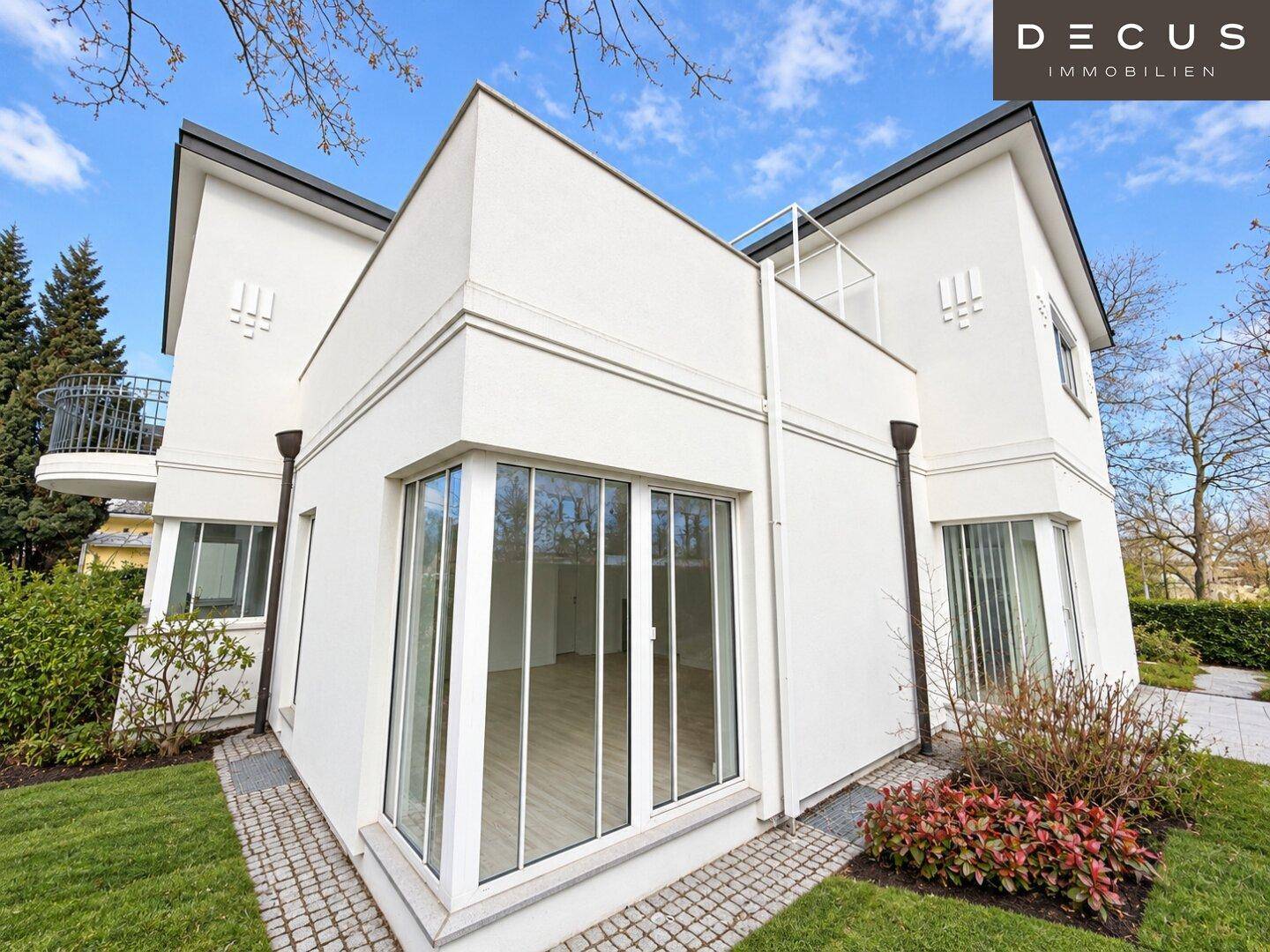 Rückansicht des modernen Hauses mit großen Fenstern und Zugang zum Gartenbereich.