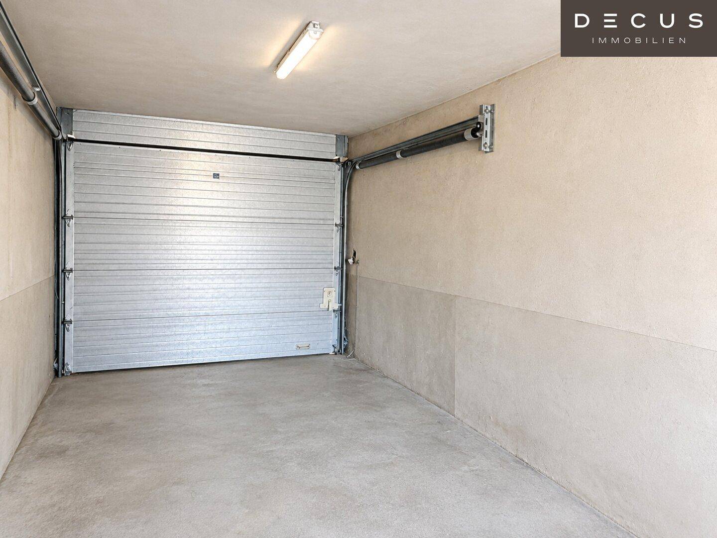 Geräumige Garage mit Rolltor und Betonboden, ideal für ein Fahrzeug.
