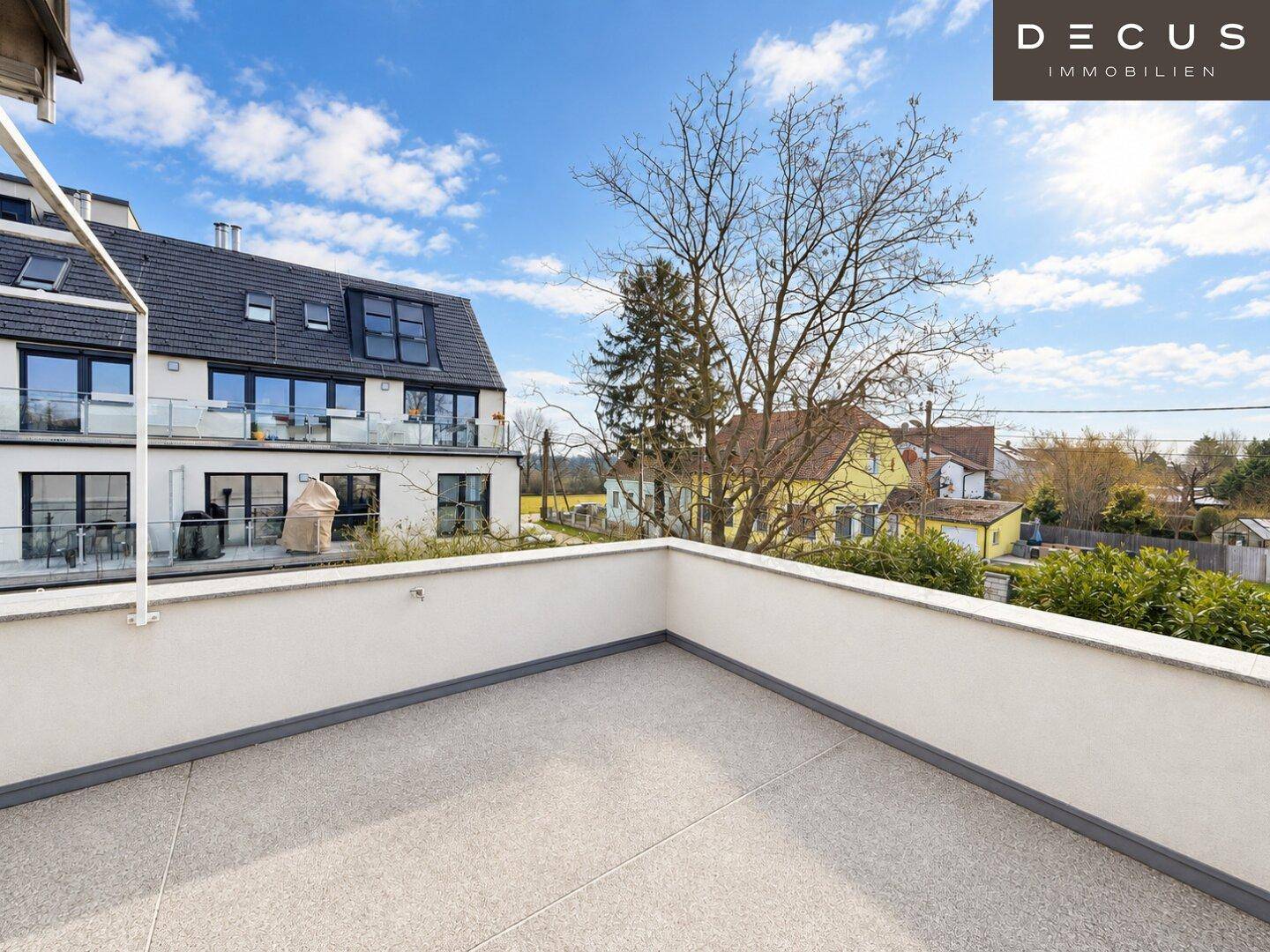 Große Dachterrasse mit weitem Blick auf die umliegende Wohngegend und den Himmel.