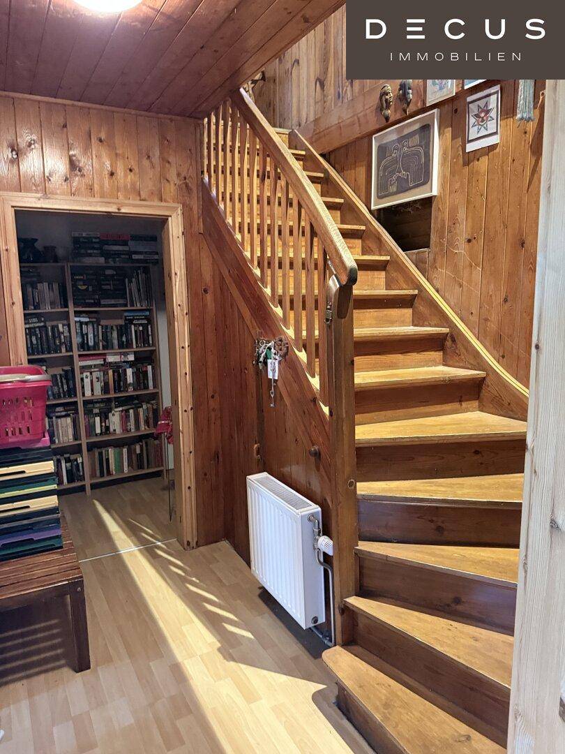 Rustikaler Flur mit Holzvertäfelung und einer Holztreppe, die zu den oberen Etagen führt.