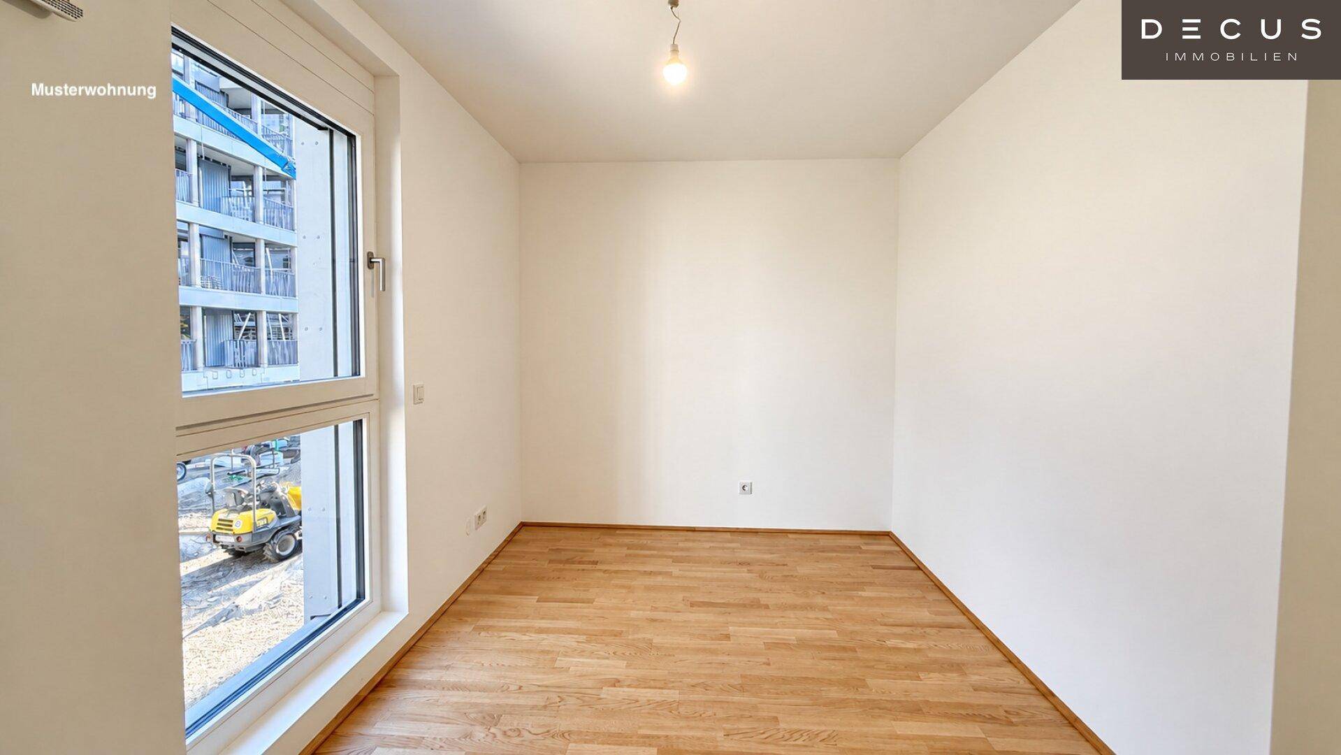Leerer Raum mit großem Fenster, das einen Blick auf die Baustelle bietet, und hellem Holzfußboden.